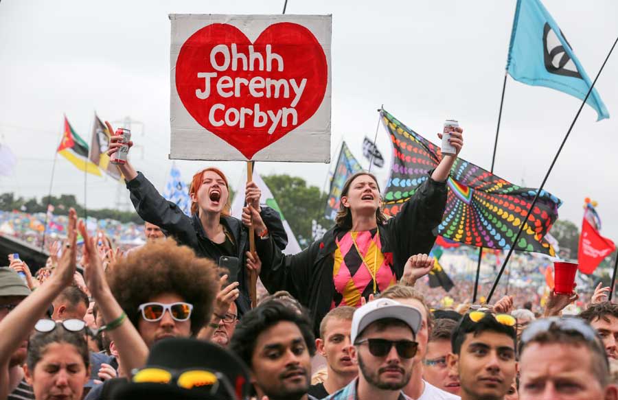 Festival goers at Glastonbury holding aloft a placard reading "Ohhh Jeremy Corbyn"