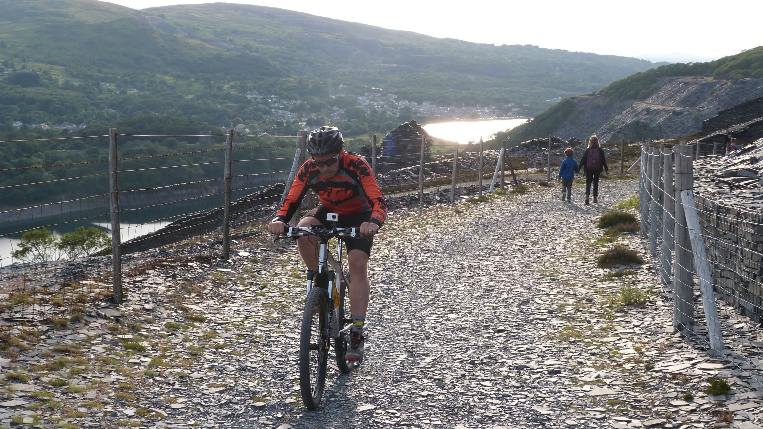 Beiciwr yn mynd ar hyd llwybr cyhoeddus sy'n mynd drwy'r chwarel