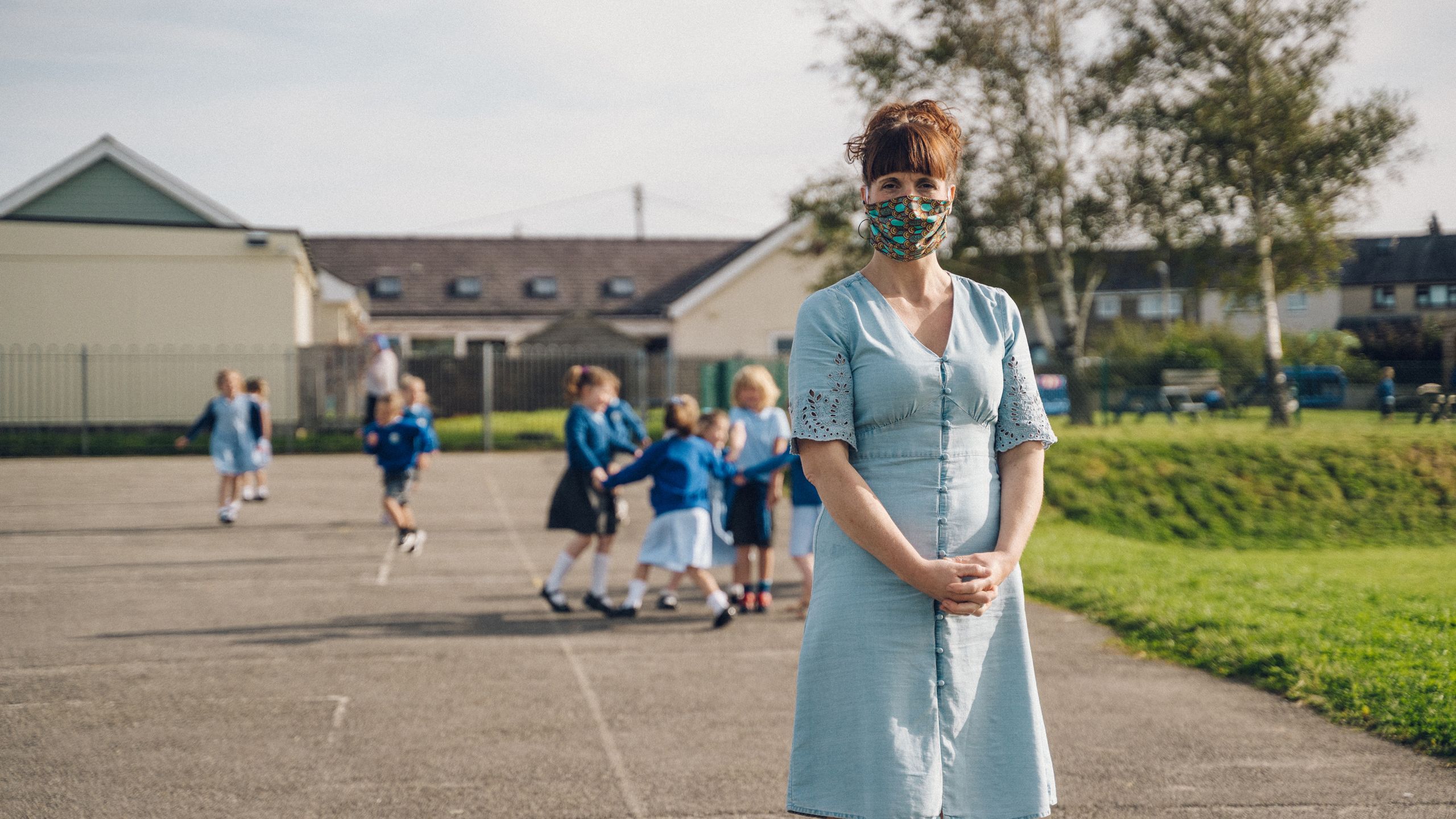 Athrawes ar iard yr ysgol yn gwisgo masg