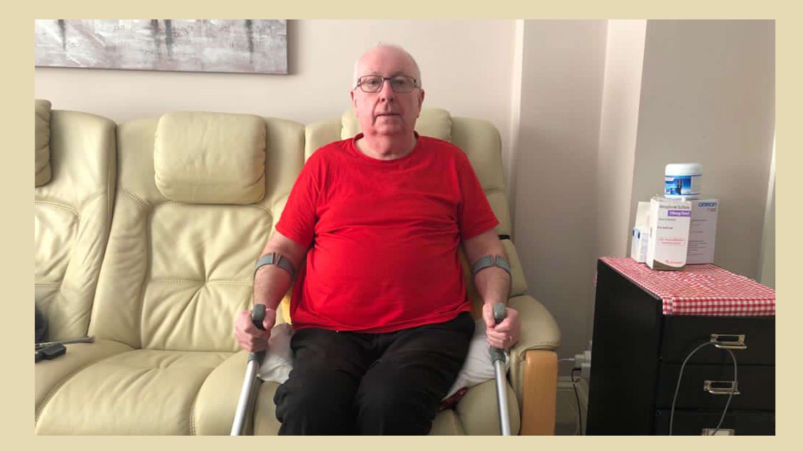 Colin Jones yn eistedd ar y soffa gyda'i faglau