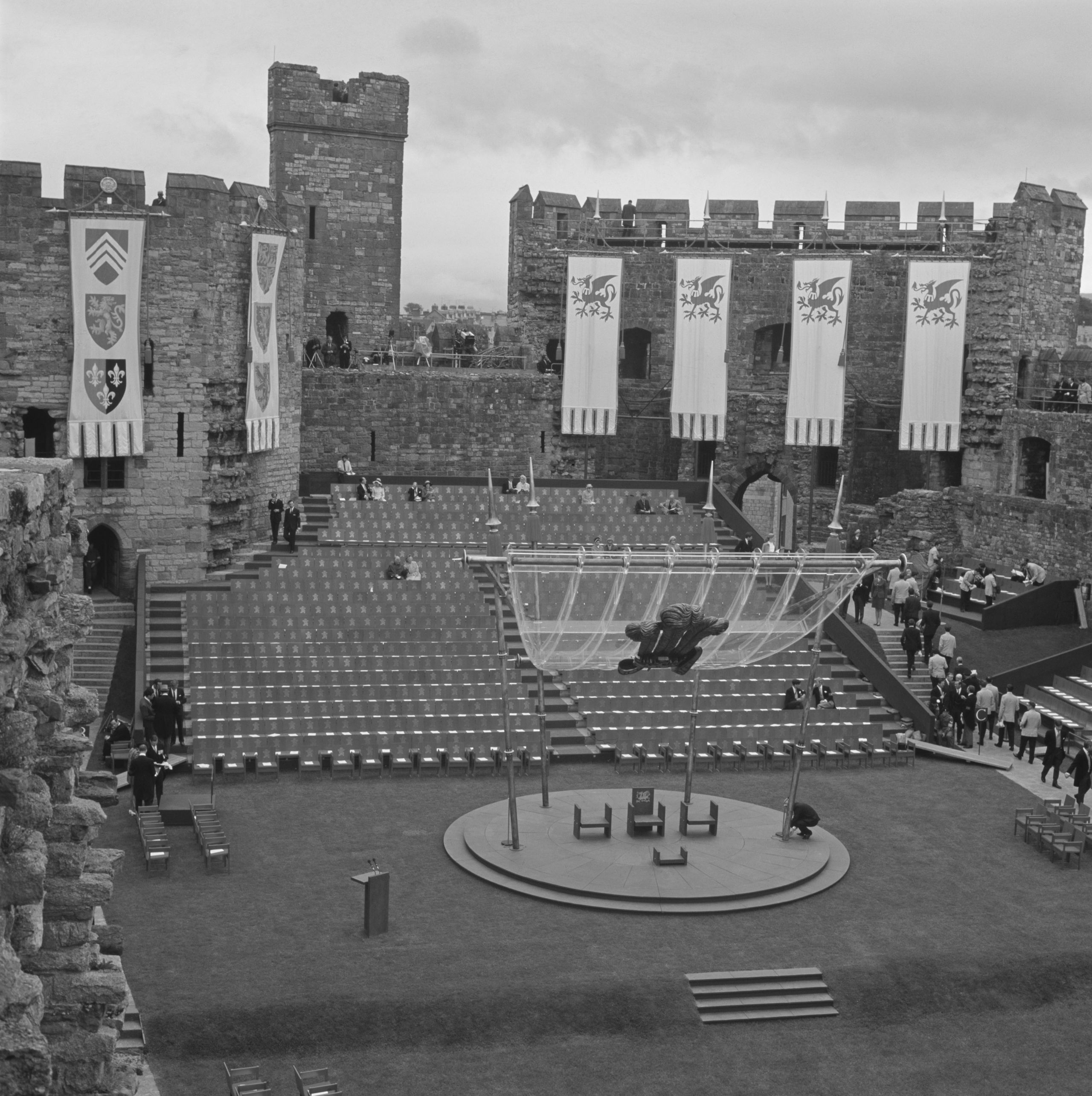 Llun du a gwyn o lwyfan yr arwisgo - a rhai o'r gynulleidfa yn dechrau cyrraedd