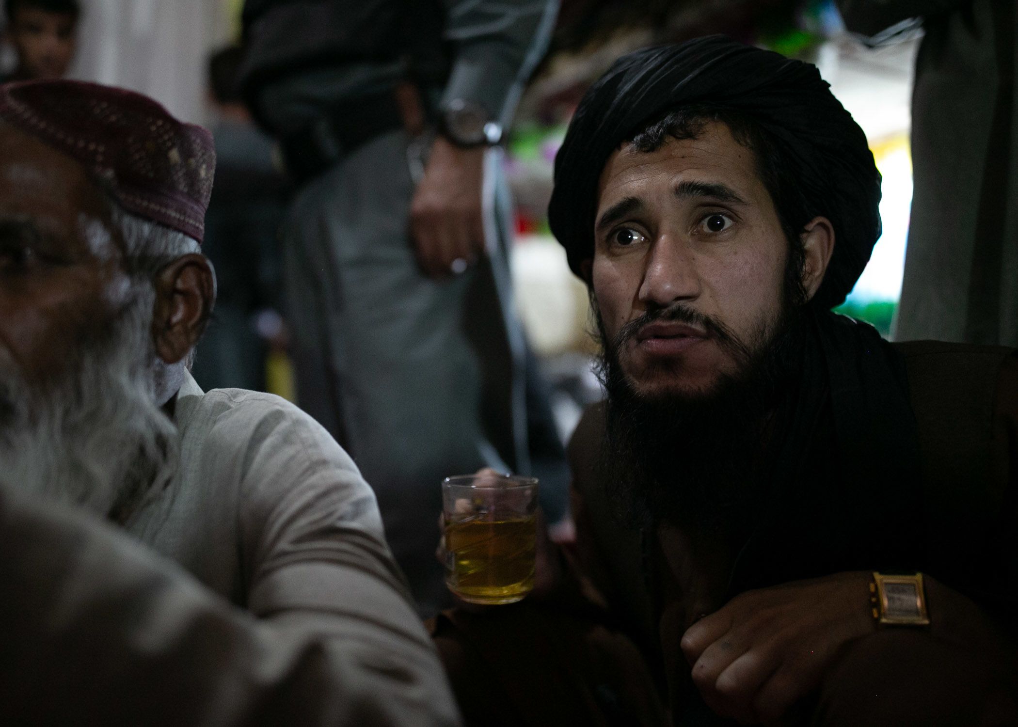 A Talib inmate clasping a cup of green tea listens intently to his elders