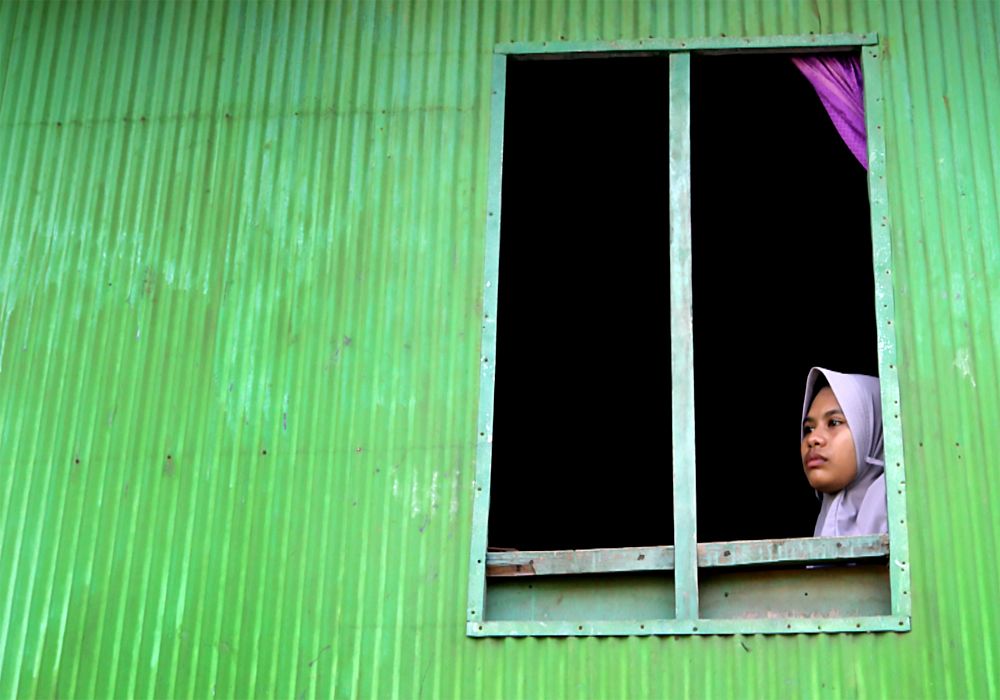 Rosa Saphira, looks out of a window at her home in Komodo village, Komodo Island, Indonesia. BBC