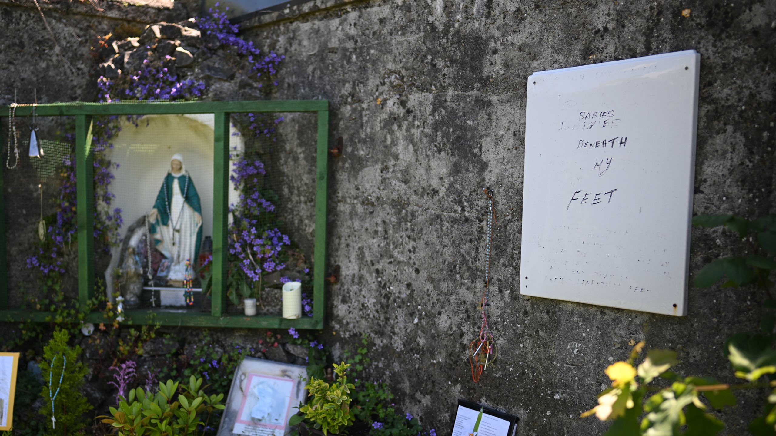Memorial statue left on the site at Tuam beside a hand written note saying 'babies beneath my feet'.