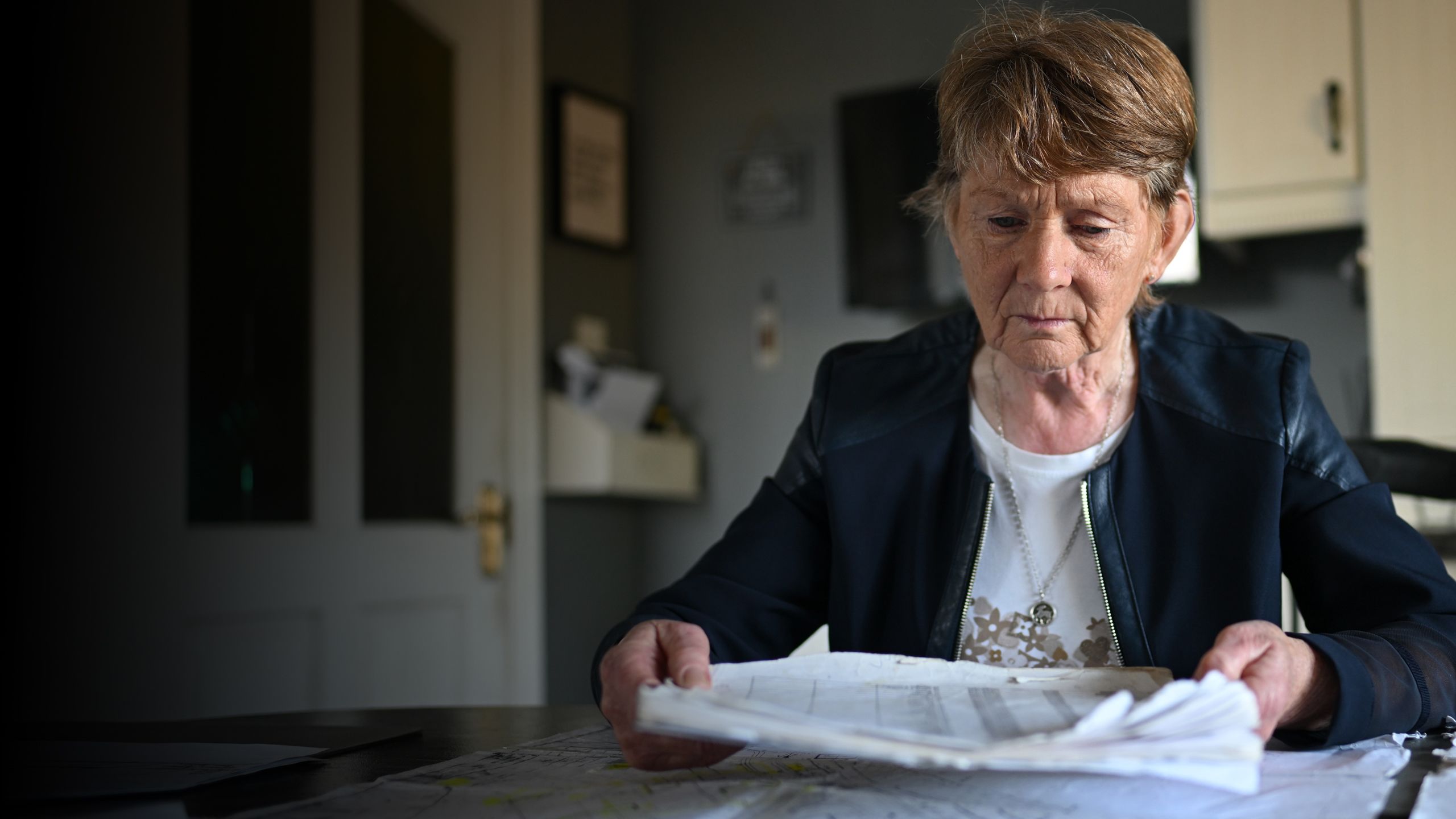 Catherine Corliss, dressed in a black jacket looking at plans of the site in front of her.