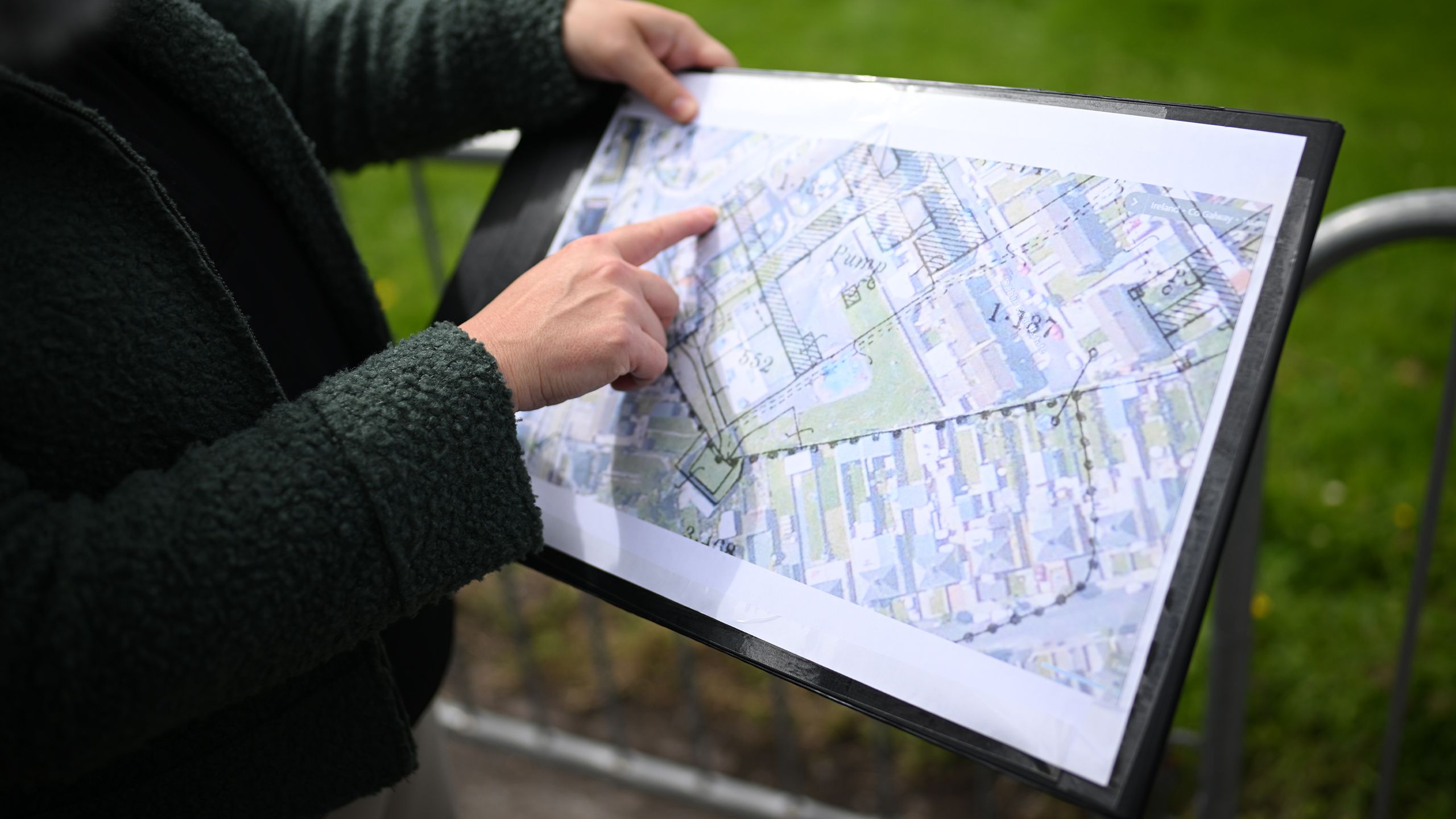 A person pointing at a printed copy of the site plans, highlighting areas to be investigated as part of the excavation..