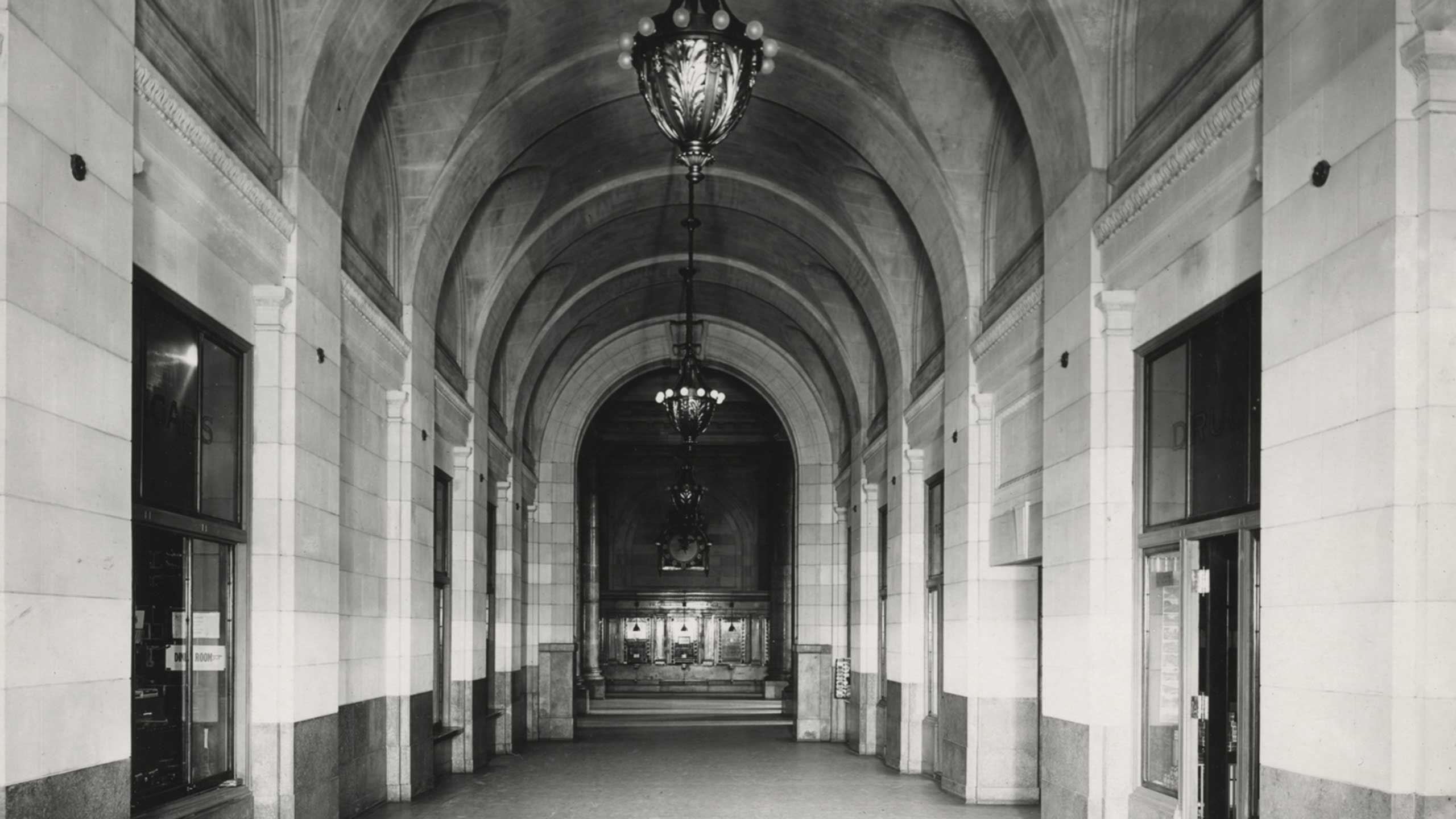 Corridor leading to ticket hall, pictured during the station's heyday, fades to the same scene, covered in scaffolding today