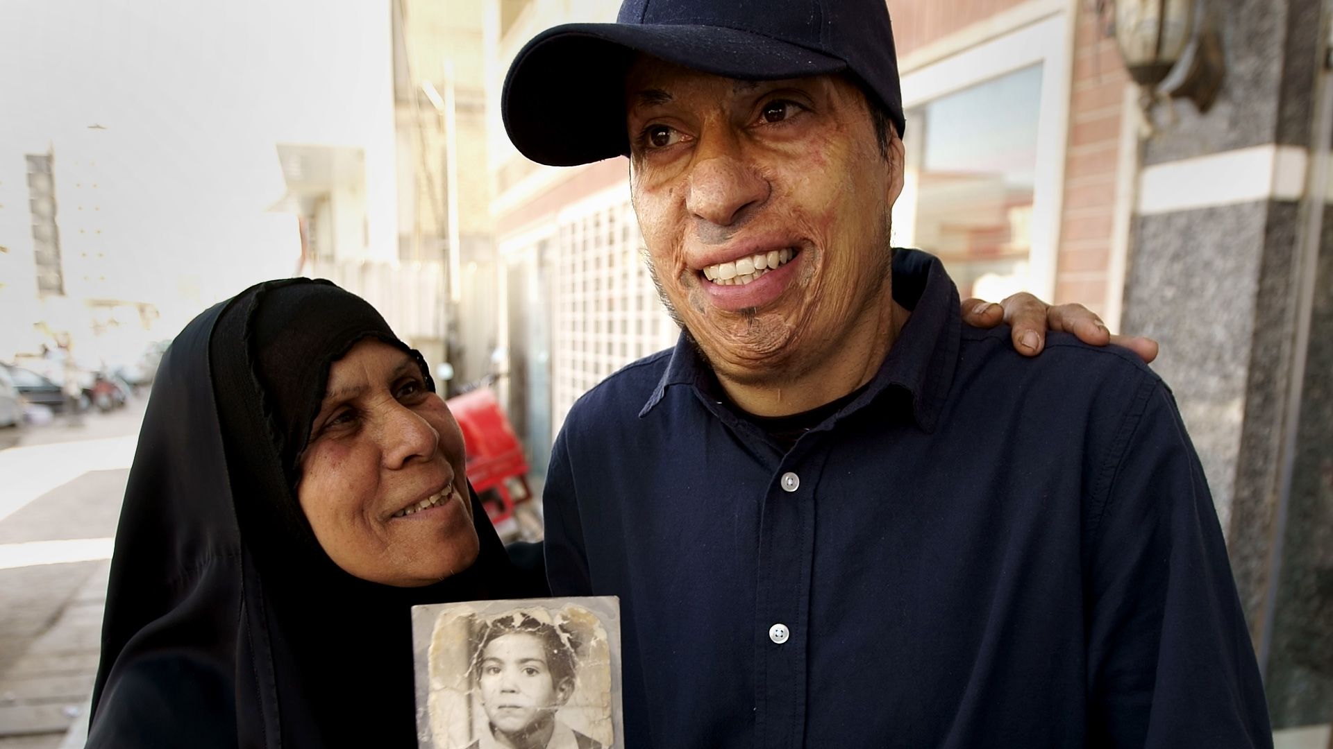 Amar with his mother, clutching the boyhood photo of himself