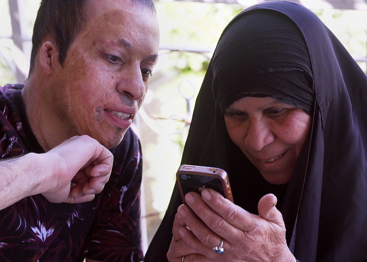 Amar shows his mother some pictures on a mobile phone