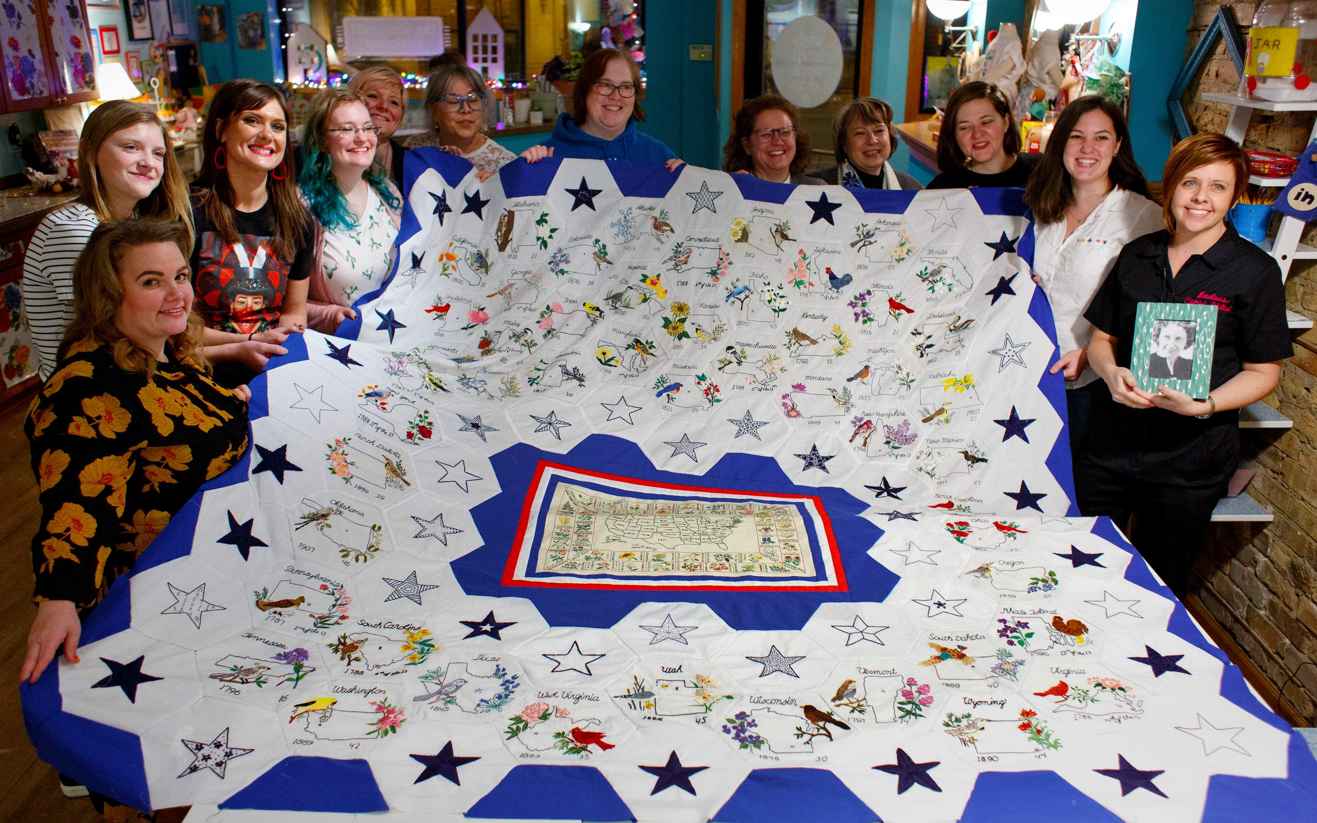 Quilters hold up Rita's completed quilt
