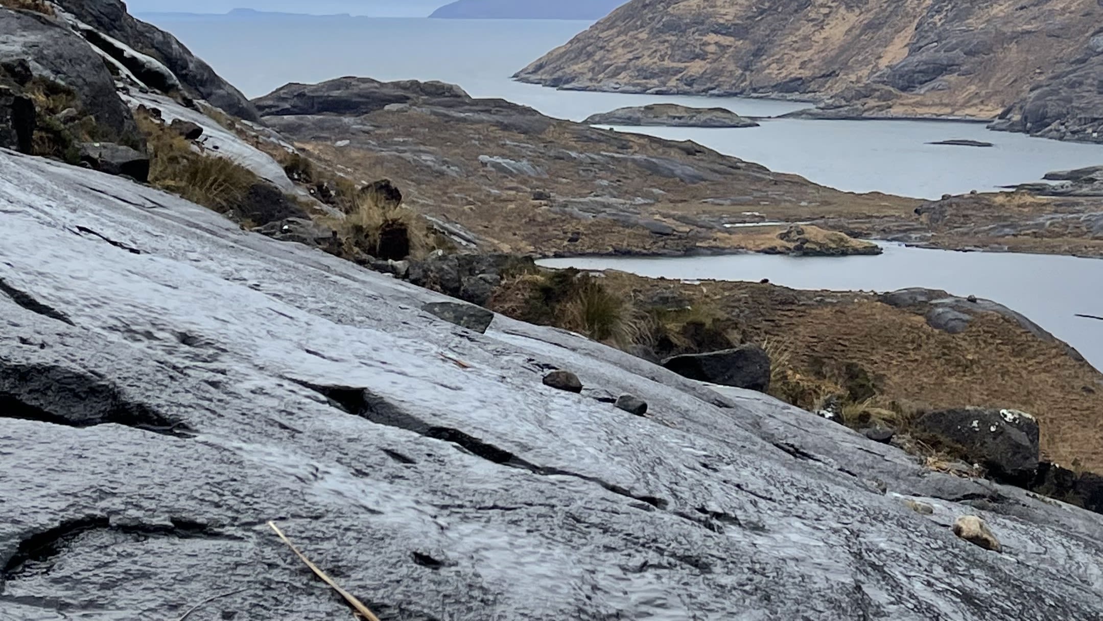 Gabbro rock on which John slipped, with mountains and water in the background