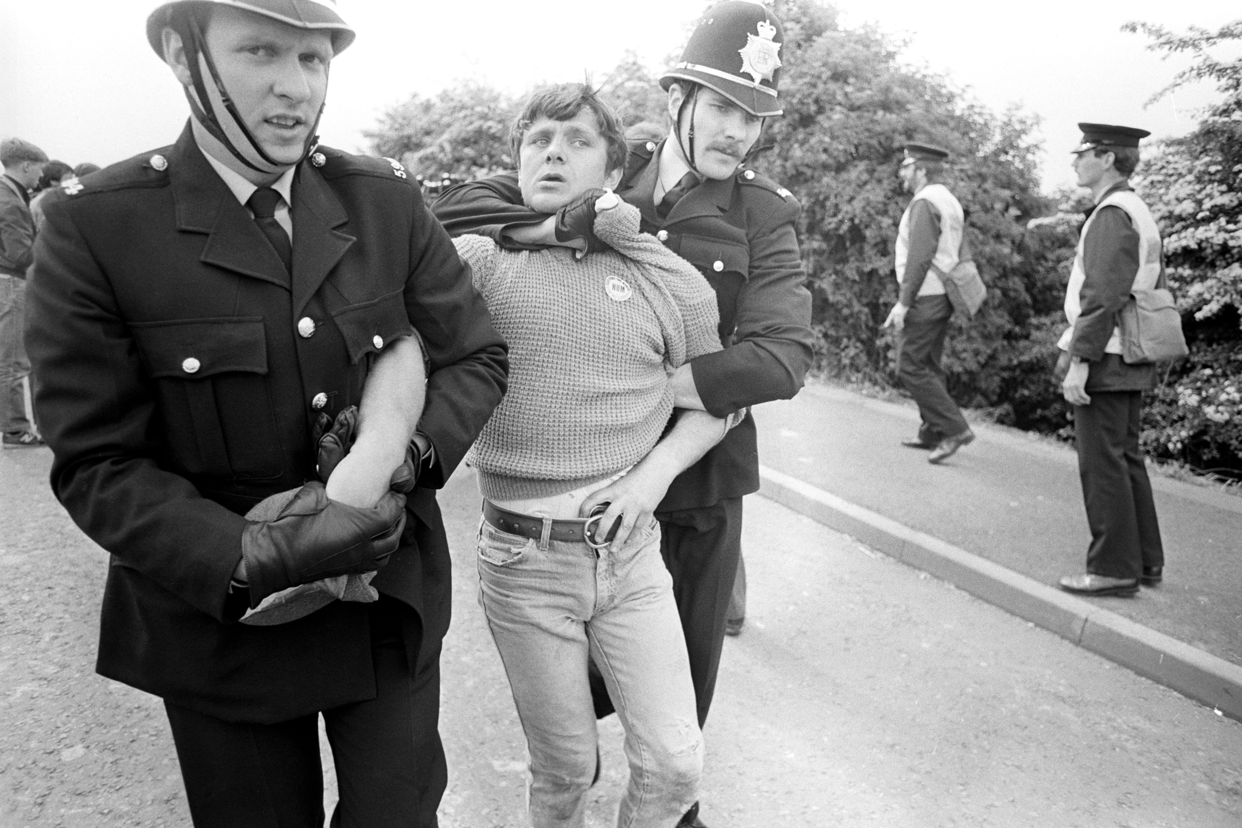 A striking miner is held around the neck by a policeman in uniform during the strike in 1984.