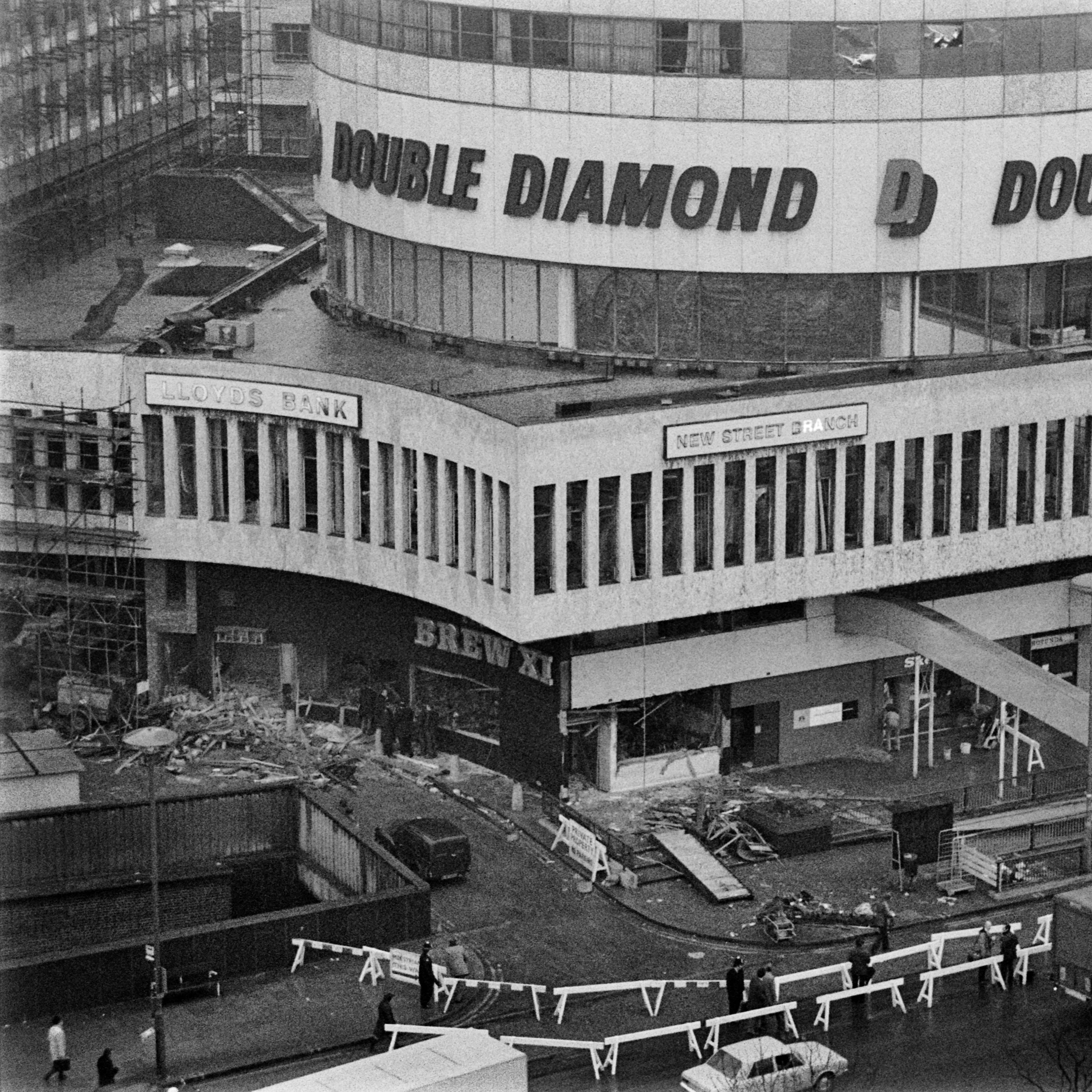 Black and white aerial photo of the devastation left by the blasts in the Mulberry Bush pub. The scene is of rubble and cordoned off areas