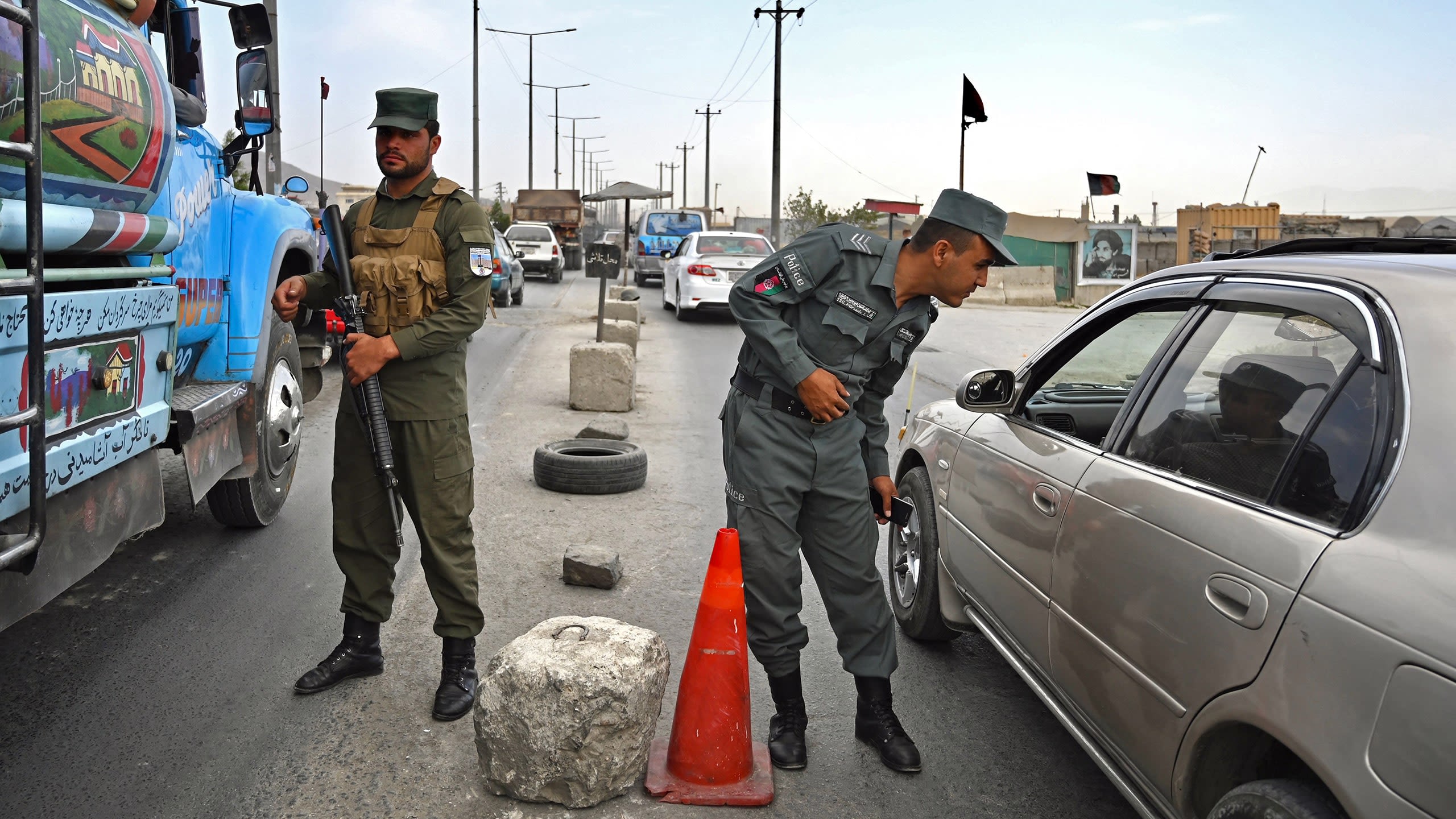 Afghan policemen stand guard at a checkpoint along a road in Kabul on August 14, 2021.