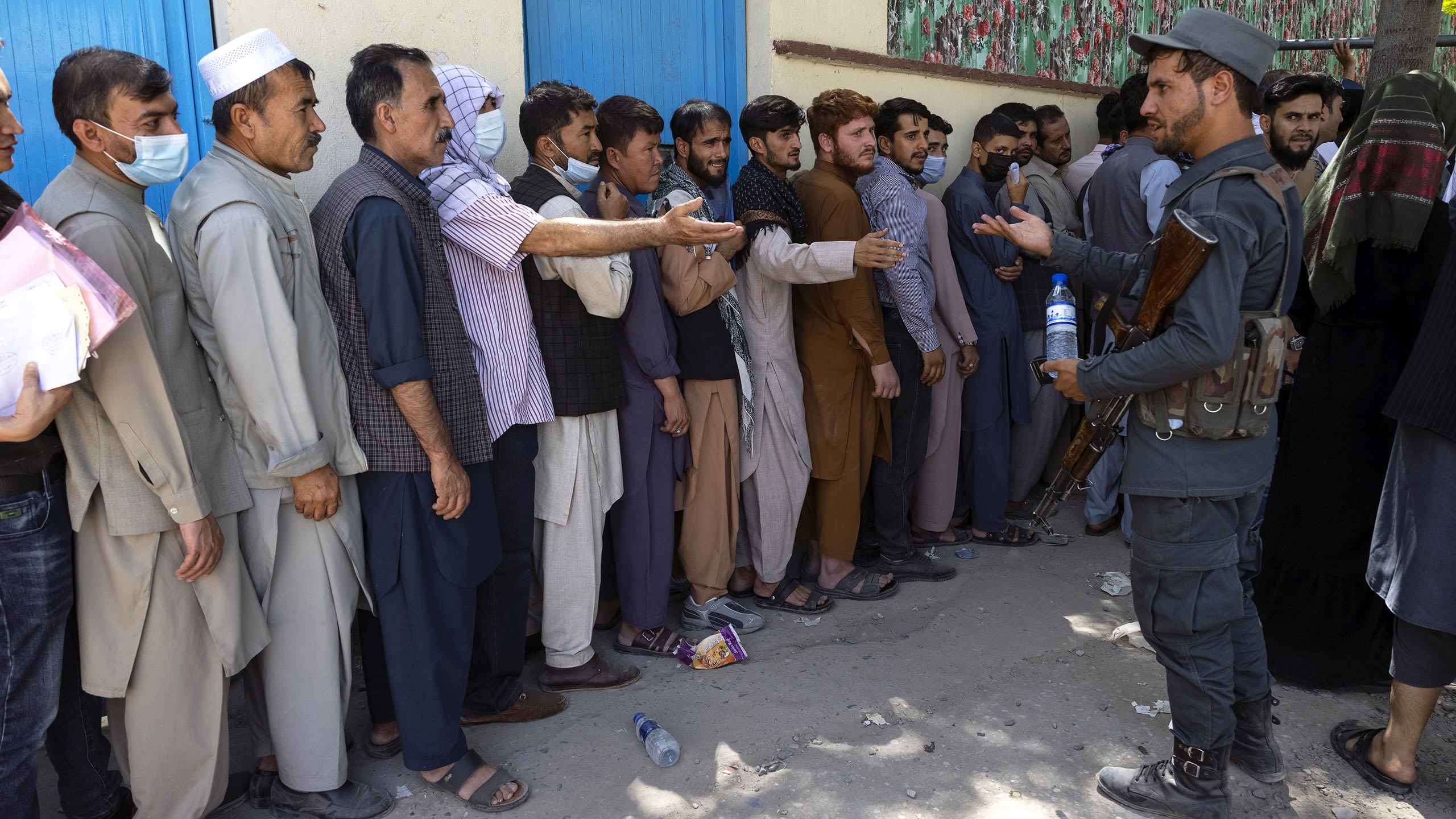 People queue for hours to get travel documents at the Kabul passport office