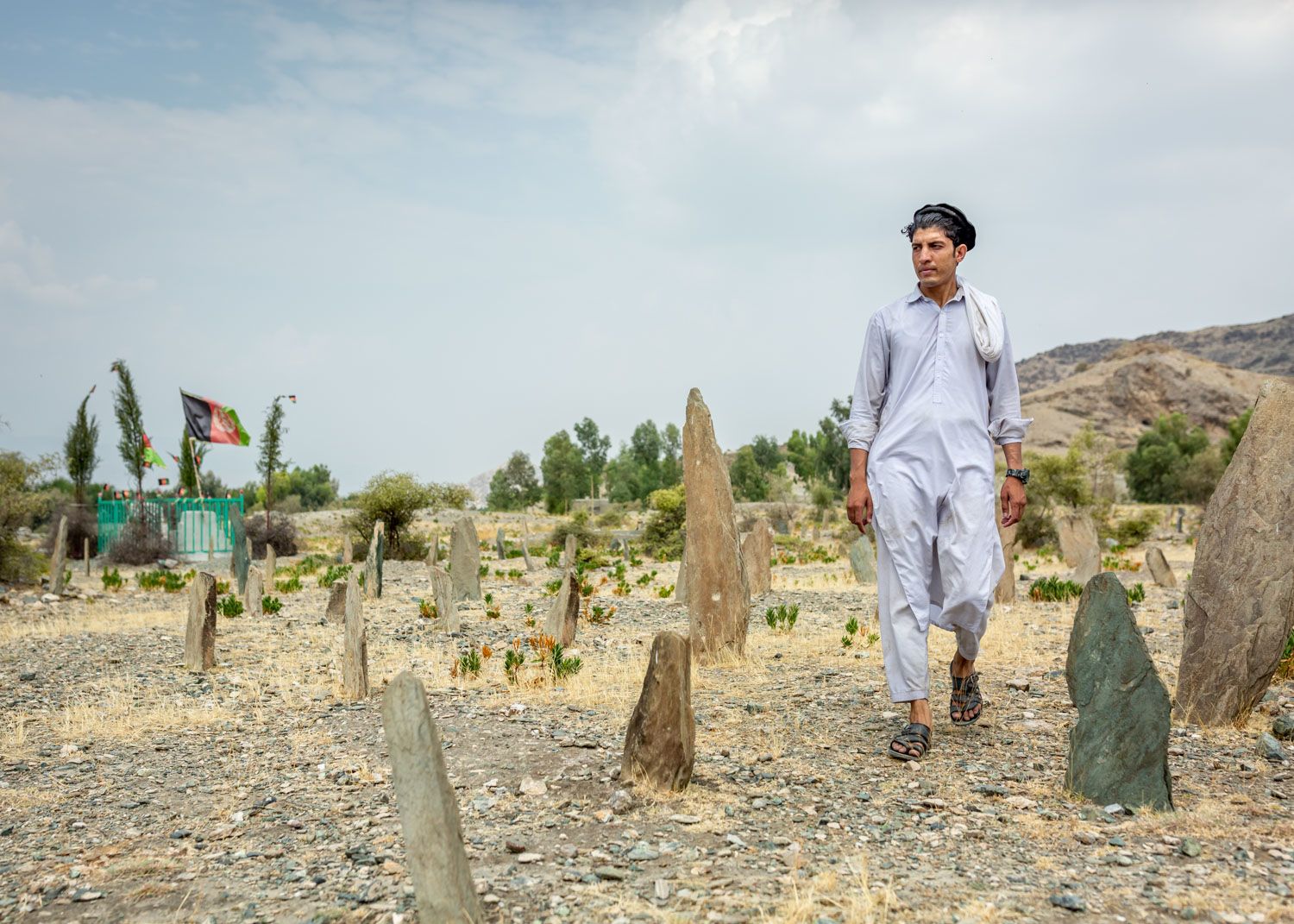 Nematullah walks through the graveyard where the fallen solider is buried