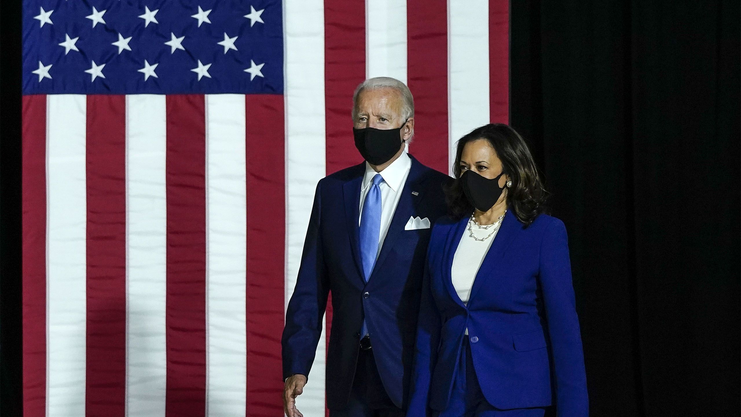 Joe Biden e Kamala Khan com a badeira americana ao fundo