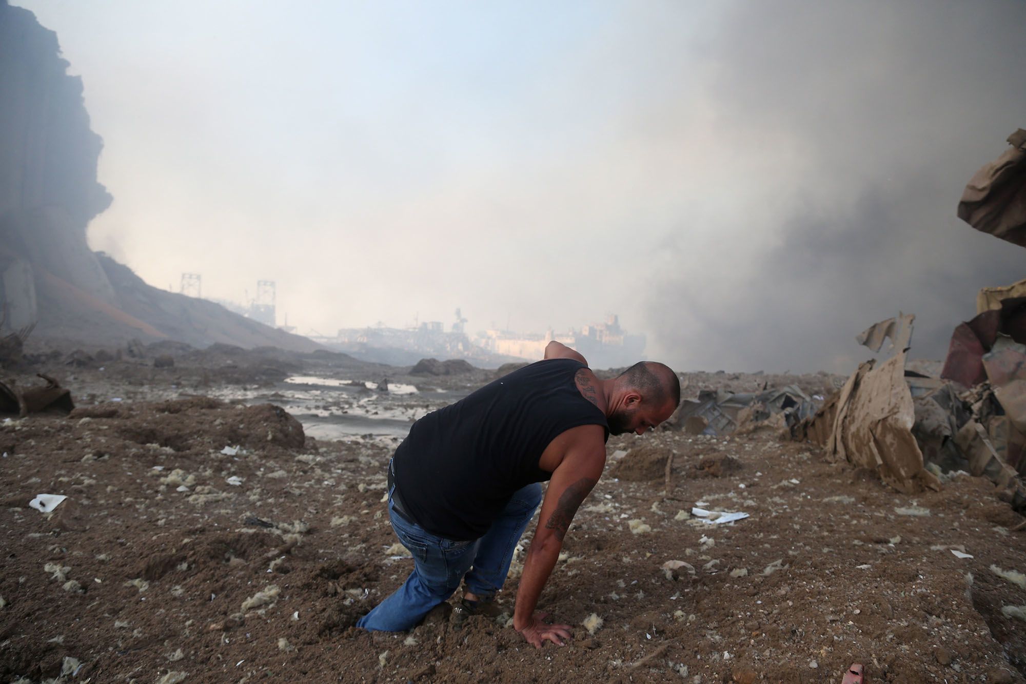 A man tries to walk in the mud near the scene of explosion at the Beirut port