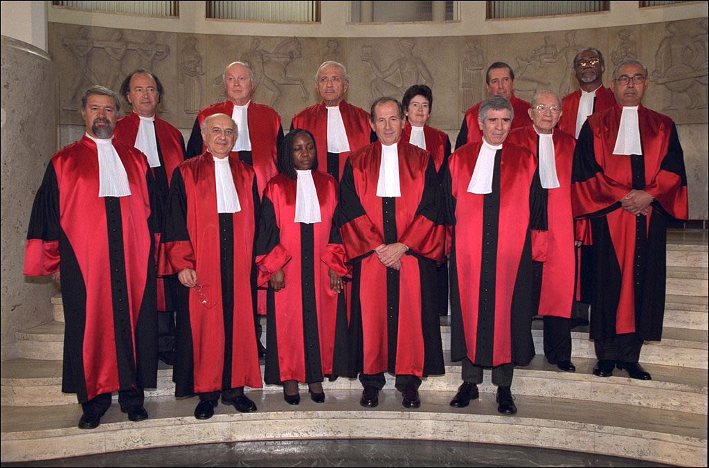 13 sudija na stepeništu u jarkim odorama, u sredini je sutkinja Florens Mumba