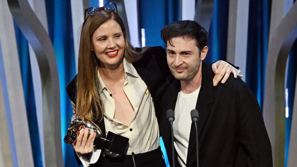 Justine Triet and Arthur Harari accept the Original Screenplay Award for 'Anatomy of a Fall' on stage during the EE BAFTA Film Awards 2024 at The Royal Festival Hall on February 18, 2024 in London, England