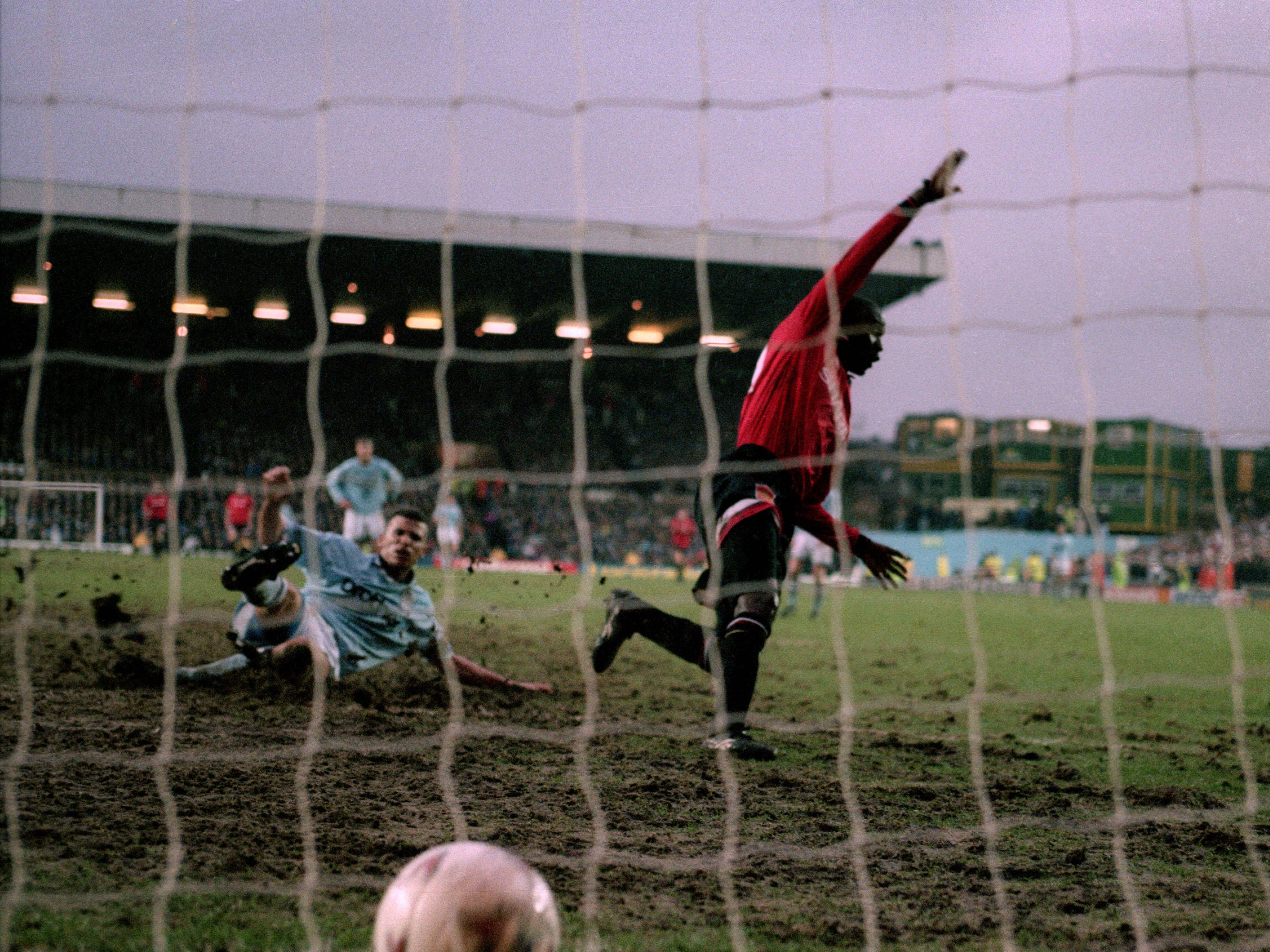 Keith Curle (left) slides in but cannot prevent Andrew Cole (right) from scoring for United against City in a 1995 Manchester derby