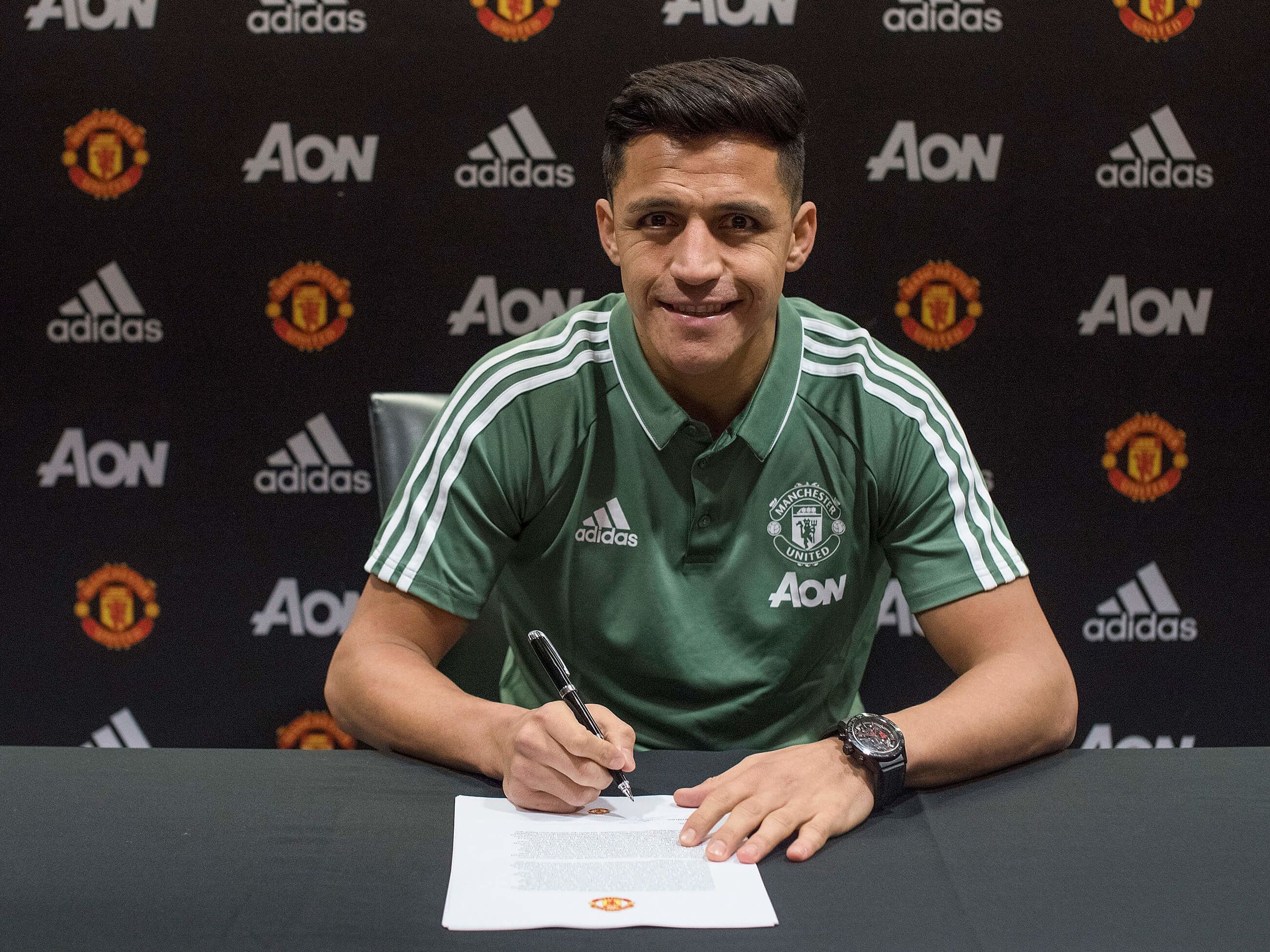 Alexis Sanchez poses with his Manchester United contract