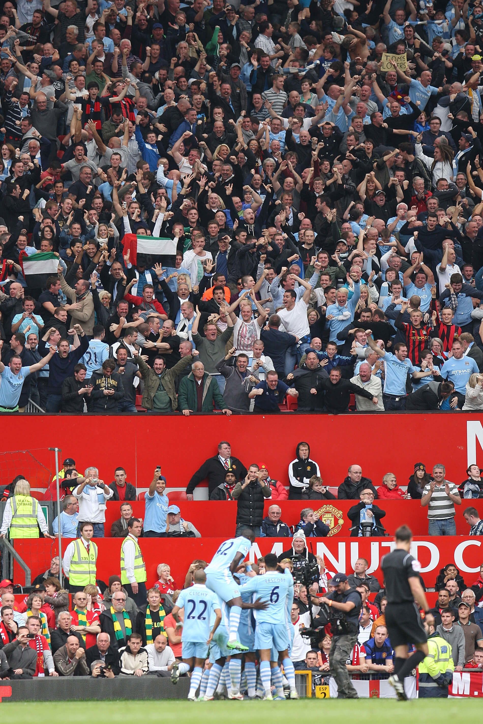 Manchester City players celebrate Sergio Aguero's goal in front of their fans in the 6-1 win at Old Trafford in October 2011