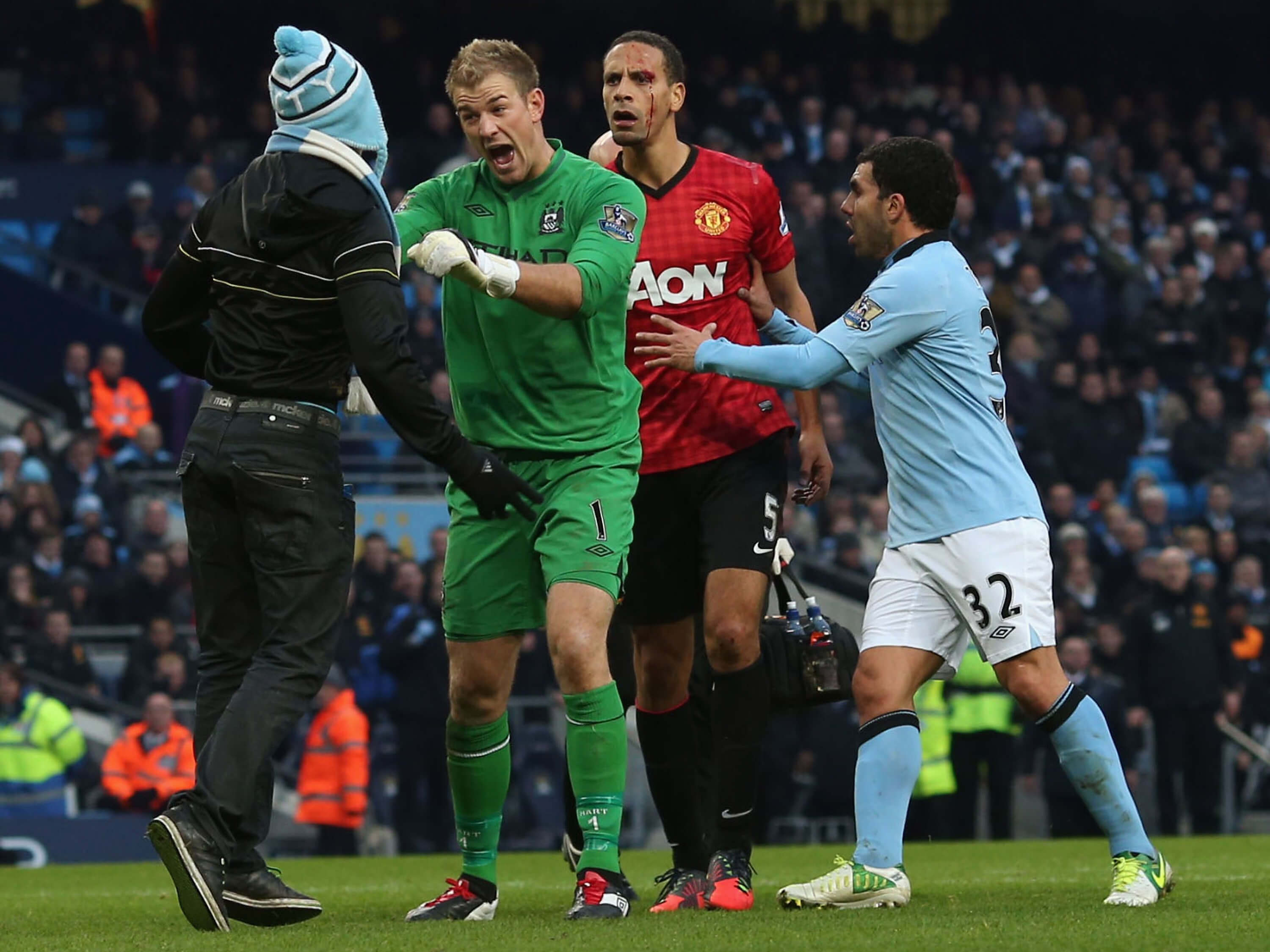 Joe Hart confronts a Manchester City fan on the pitch as Rio Ferdinand is held back by Carlos Tevez