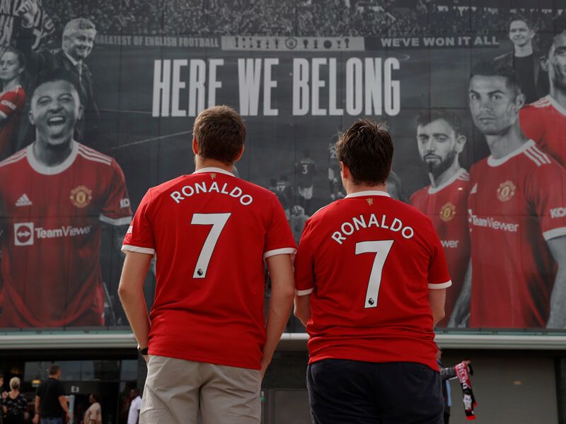 Two Manchester United fans in Cristiano Ronaldo shirts stand in front of Old Trafford