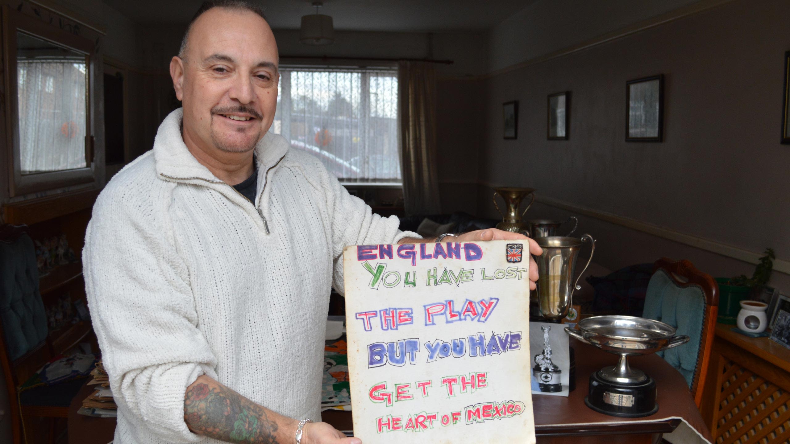 Keith Batt holding a placard reading "England you have lost the play but you have get the heart of Mexico"