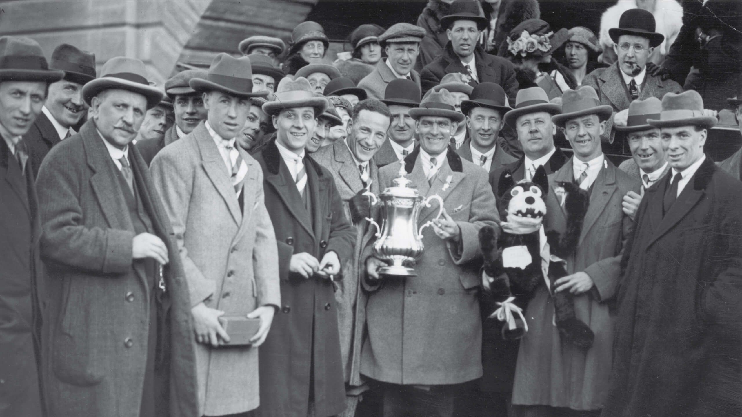 Bolton Wanderers team captain Joe Smith (surrounded by his team-mates) holds the FA Cup trophy outside the stadium after the match