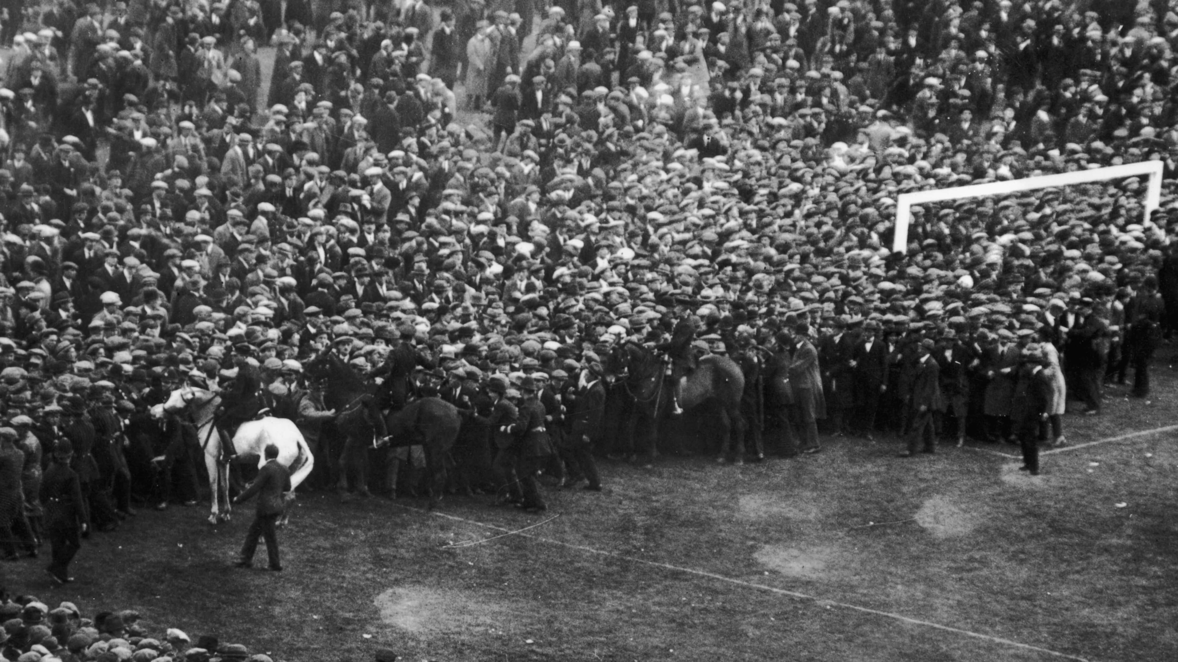 George Scorey on horse Billy help to usher crowds from the Wembley pitch before the 1923 FA Cup final