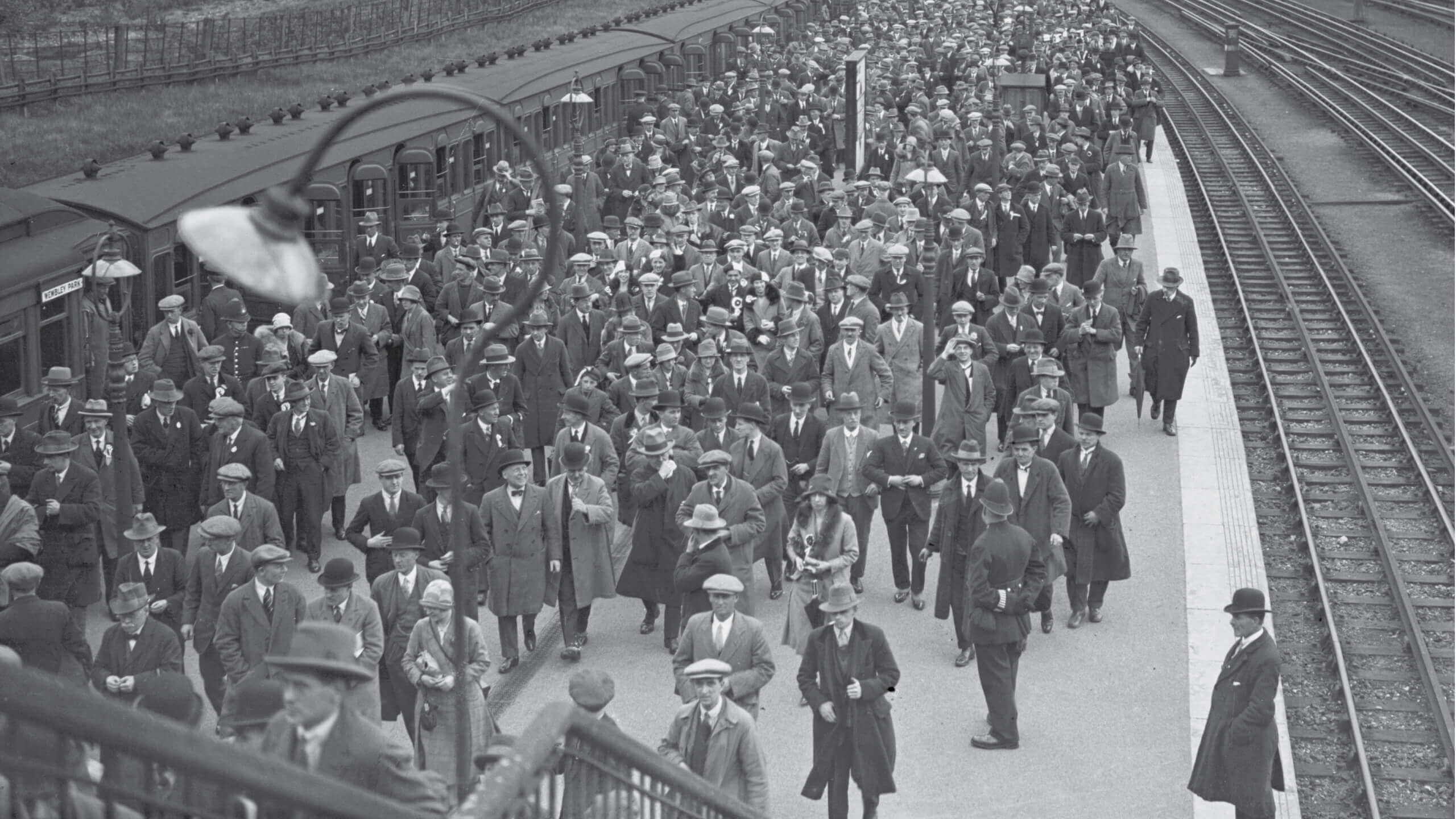 Fans disembark a train and walk along the station platform at Wembley ahead of the 1923 FA Cup final