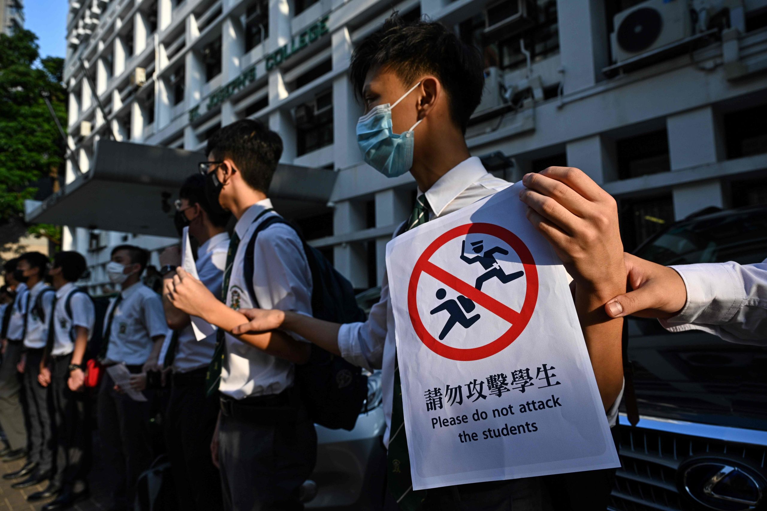 香港中半山聖約瑟書院外一名參與「反送中」人鏈抗議的中學生展示以港鐵車站標示風格繪製之「請勿攻擊學生」標語牌（9/9/2019）（圖片來源：AFP）