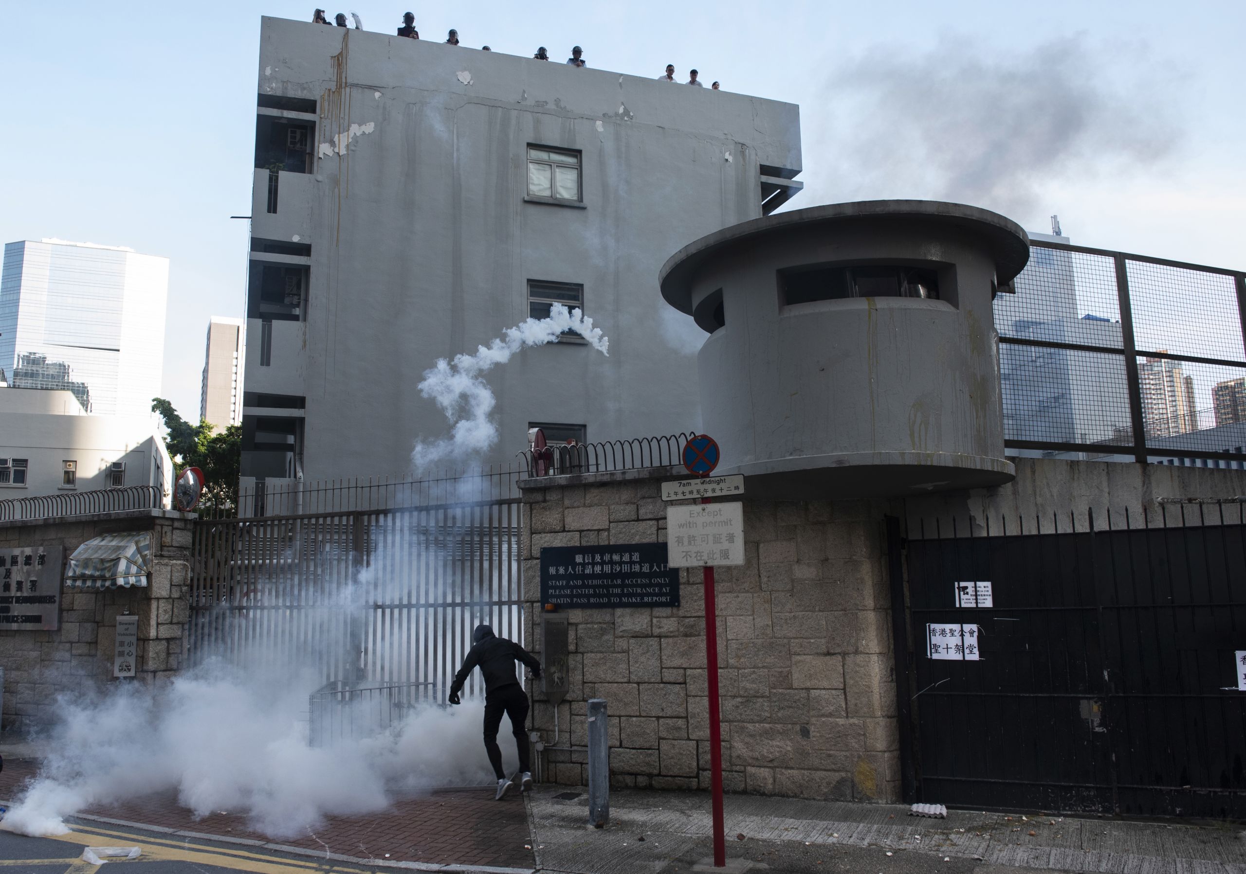 香港九龍黃大仙警署外一名「反送中」示威者在催淚瓦斯煙霧中試圖朝警察投擲物品(5/8/2019)(圖片來源:EPA)