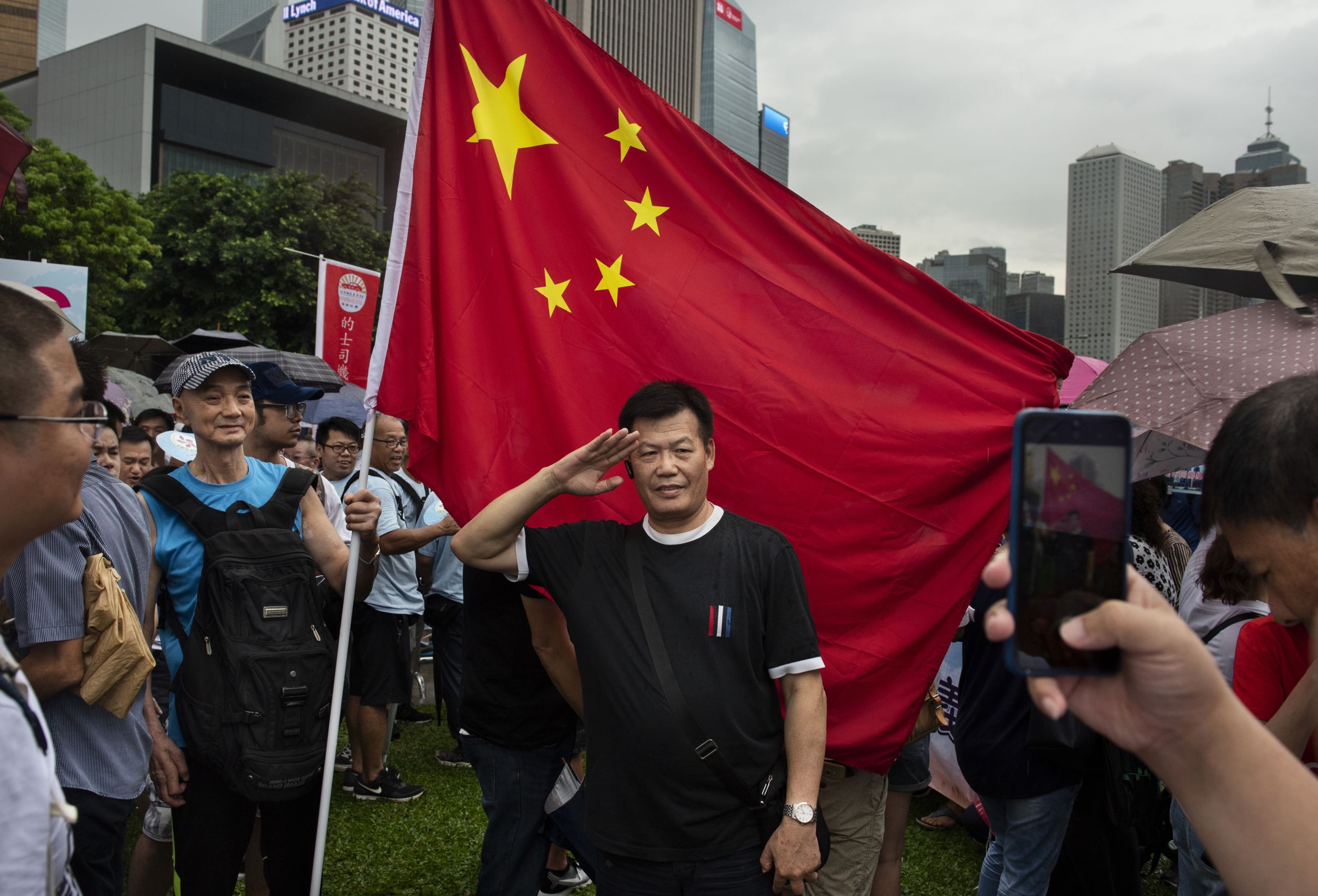 香港添馬公園親北京、親警察陣營集會上一名男子站在中國國旗前擺出敬禮姿勢拍照(20/7/2019)(圖片來源:SOPA Images/LightRocket via Getty Images)
