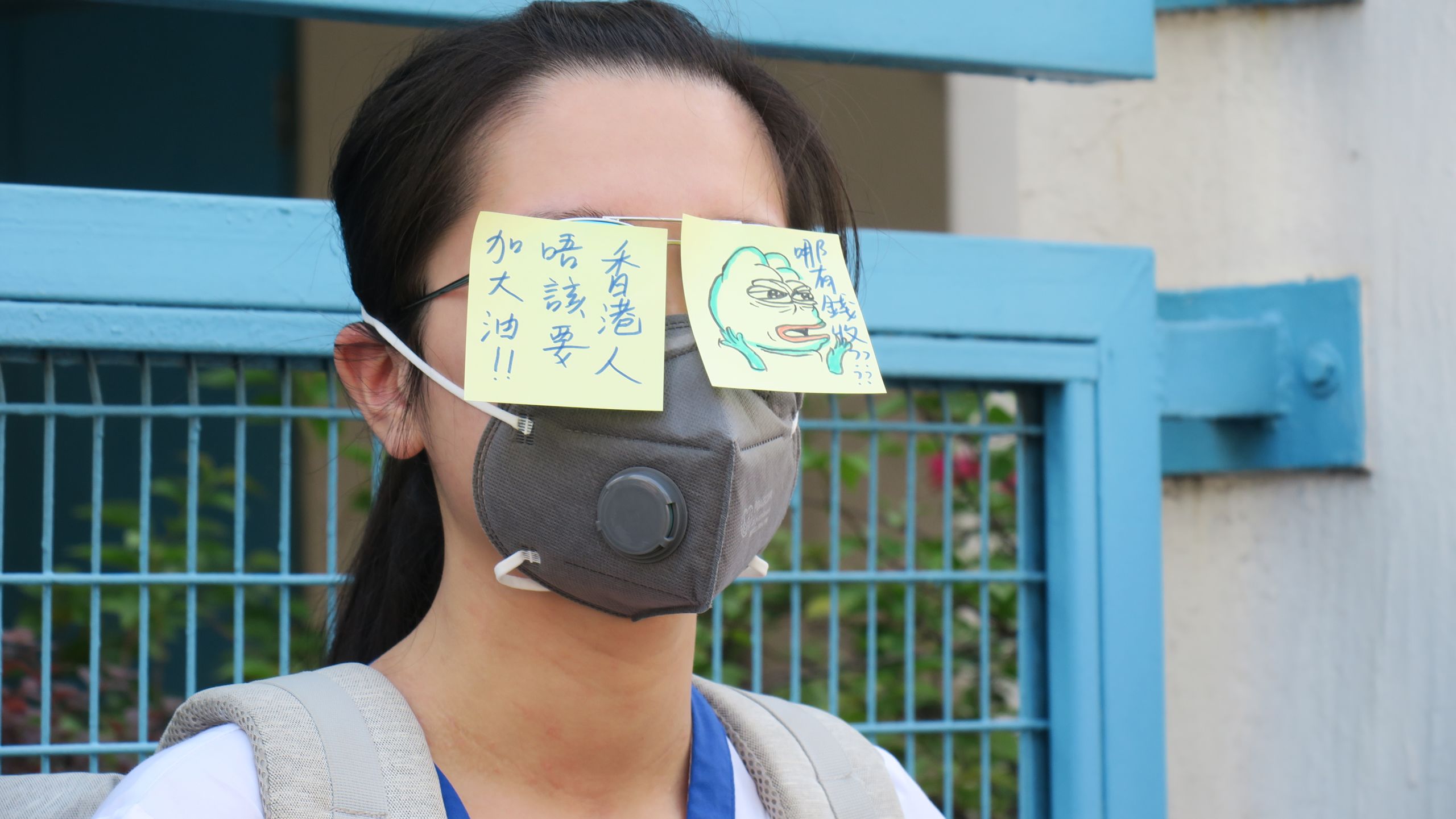 香港新界元朗大球場外一名參與「反送中」人鏈抗議的女中學生在校服上張貼寫有「香港人加油」與「哪有錢收」標語之便條（9/9/2019）（BBC News中文圖片）