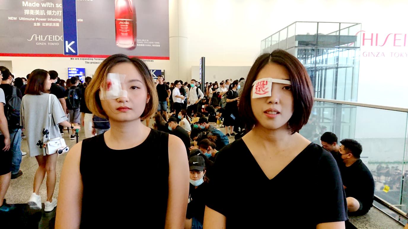 香港國際機場一號客運大樓內兩名蒙上右眼的「反送中」女示威者(12/8/2019)(BBC News中文圖片)