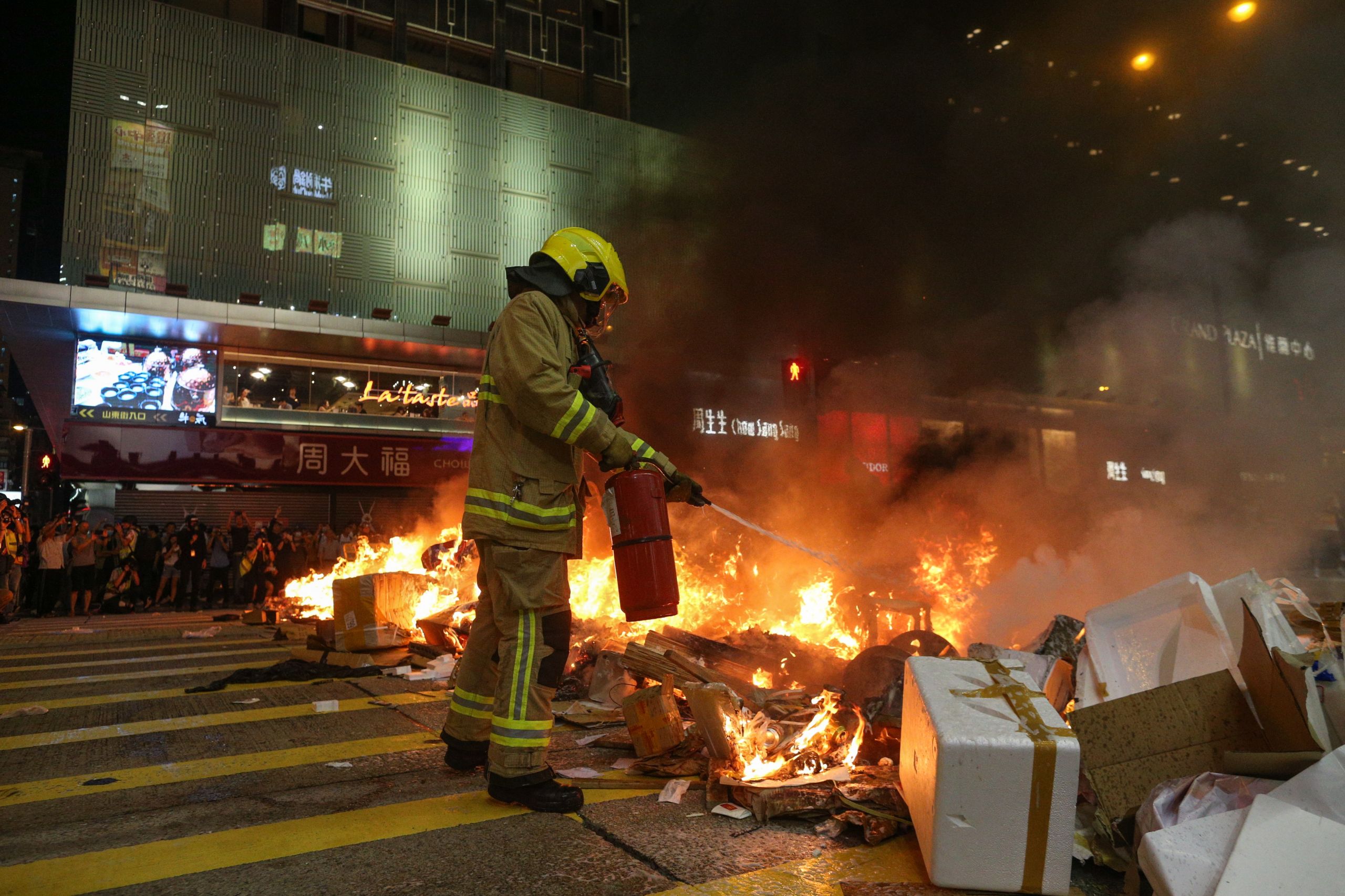 香港九龍旺角「反送中」衝突現場一名消防員試圖用滅火筒撲救焚燒中的示威者路障(6/9/2019)(圖片來源:EPA)