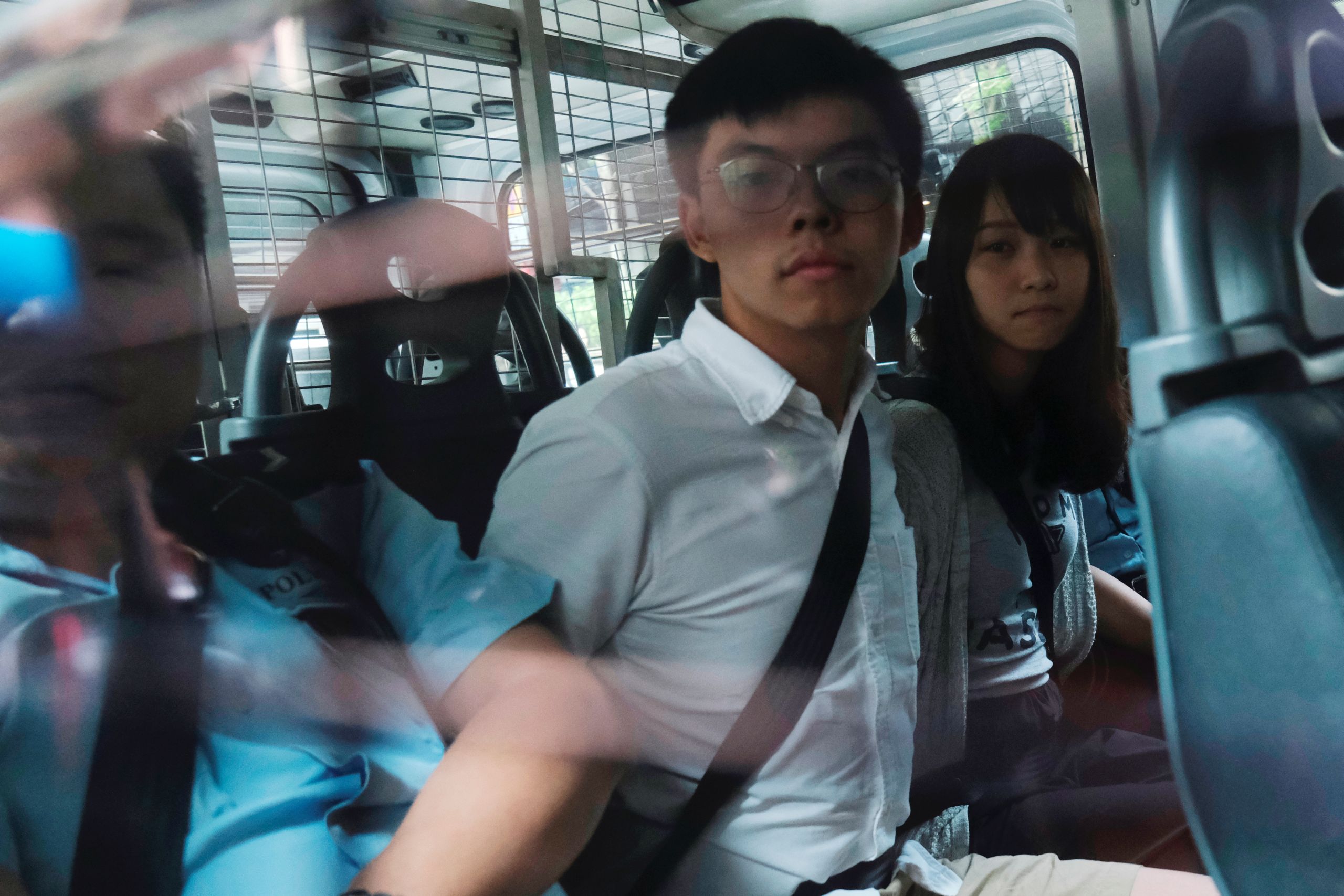 香港眾志秘書長黃之鋒(中)與成員周庭(右)由警車押送往香港東區裁判法院提訊(30/8/2019)(圖片來源:Reuters)