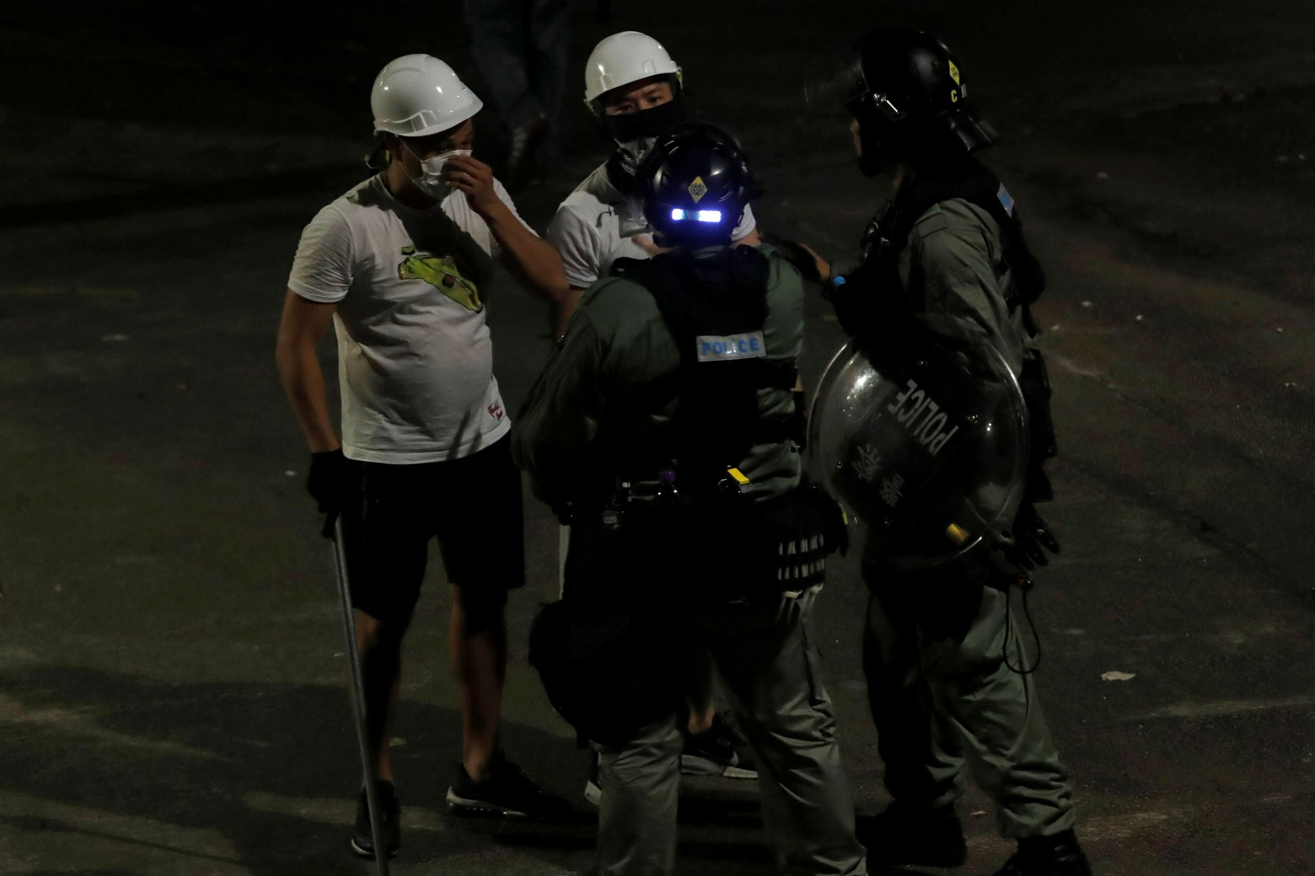 香港新界元朗南邊圍旁空地手持鐵棒之不明身份白衣人與防暴警察交談(21/7/2019)(圖片來源:Reuters)