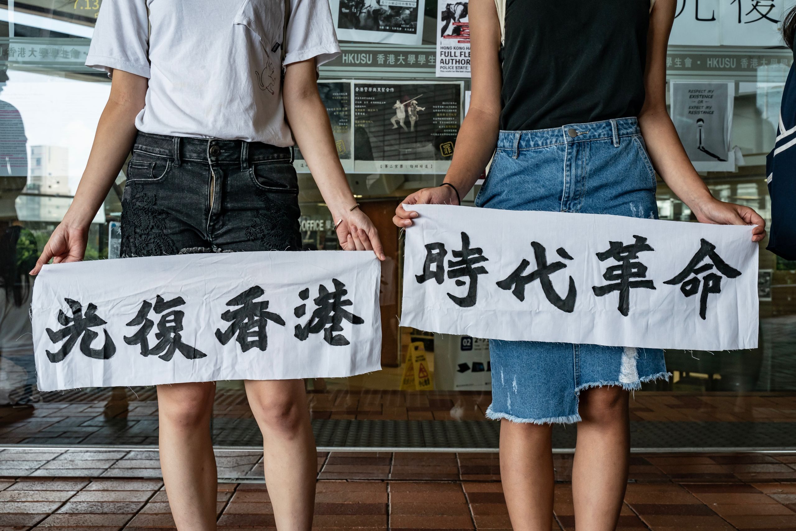 香港大學本部校園內兩名參與「反送中」示威之女學生展示「光復香港時代革命」標語(9/9/2019)(圖片來源:Getty Images)