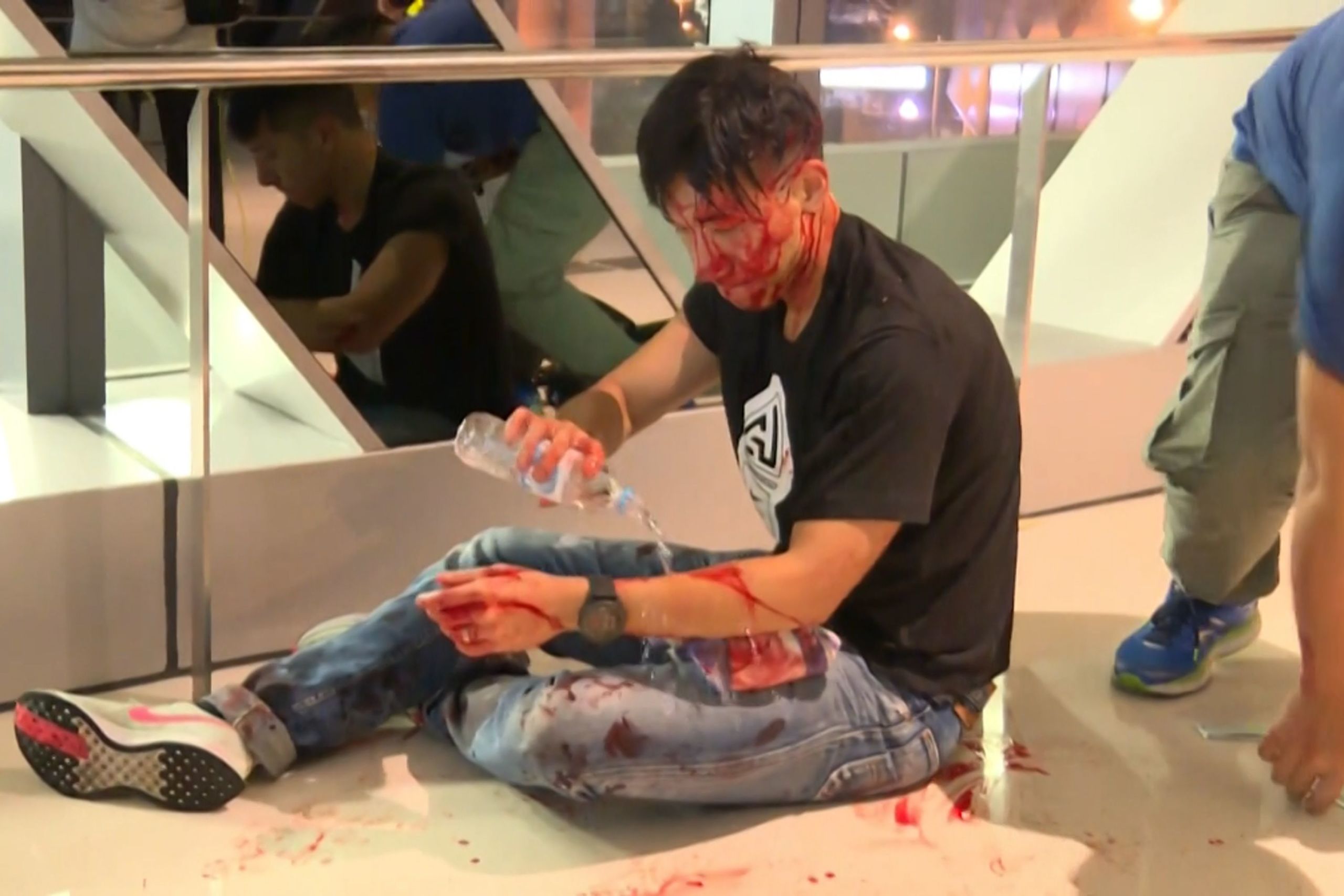 香港新界港鐵元朗站檢票大廳被不明身份白衣人打傷之知名新聞工作者柳俊江在給自己清洗傷口(21/7/2019)(圖片來源:AFP/now新聞台截屏)