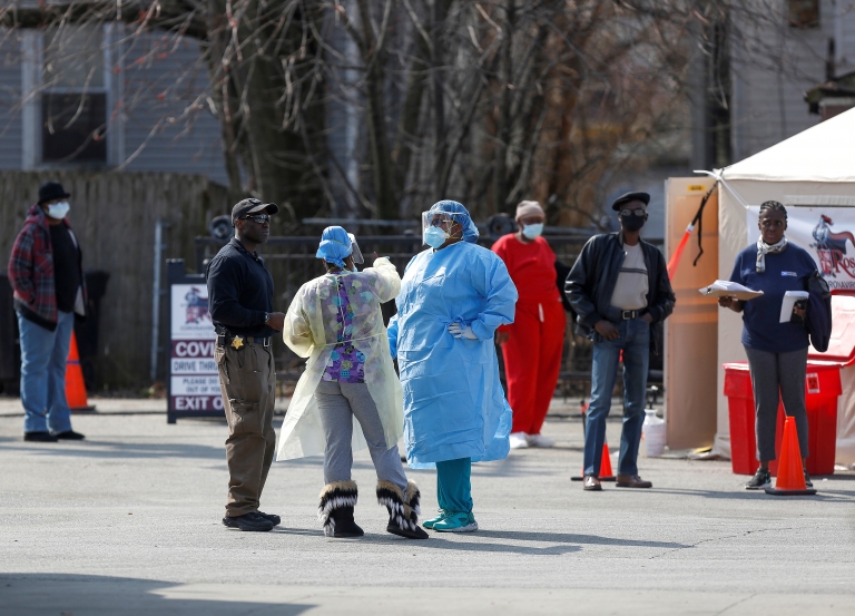 Medical workers talk as people waiting in line to receive testing outside Roseland Community Hospital in Chicago, Illinois, 7 April 2020