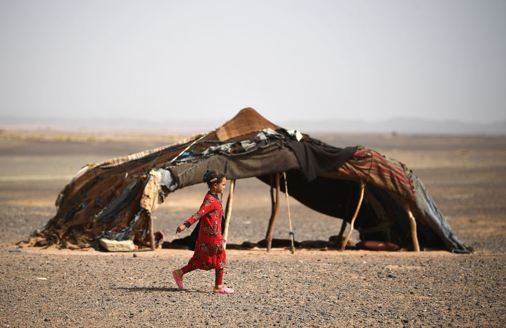 A girl walks past a tent in the Moroccan desert in May 2018