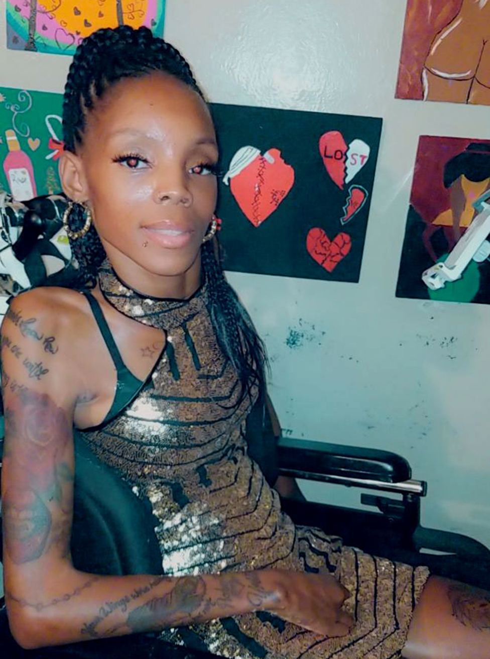 Young Black woman in wheelchair with braided hair, tattoos and wearing gold minidress 