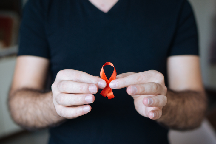 Un hombre sosteniendo un lazo rojo, símbolo de la lucha contra el sida. 