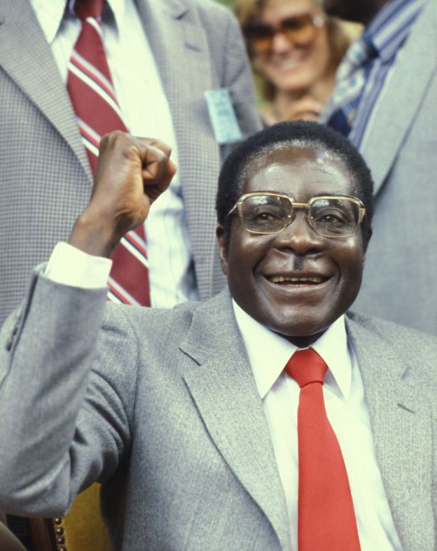 Robert Mugabe smiles and holds fist in the air, in an image from 1980 