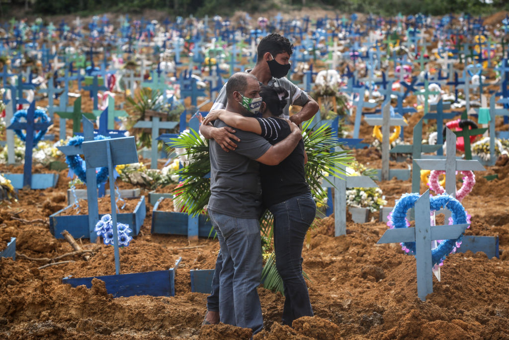 Gente abrazándose en un cementerio.