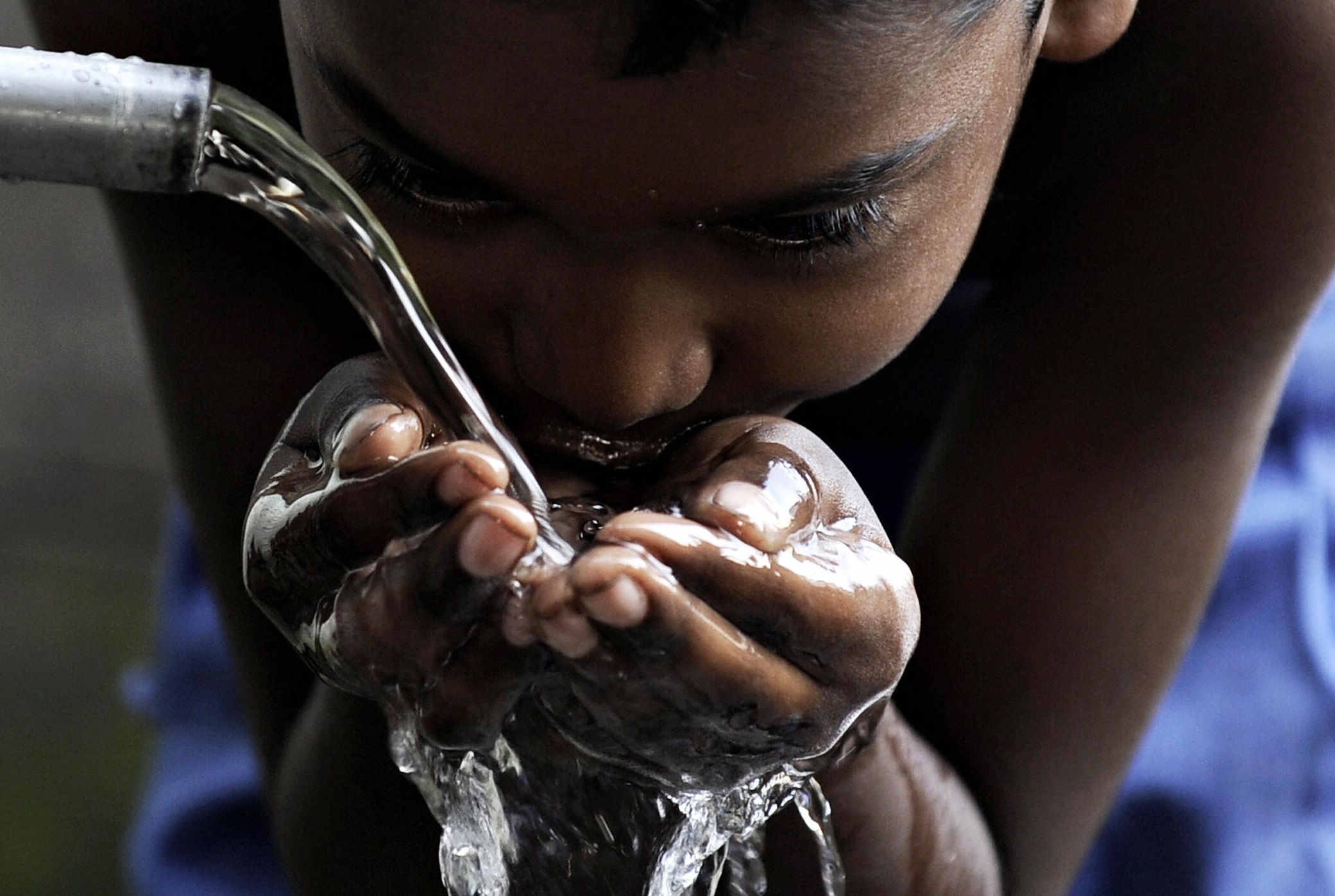 A Sri Lankan boy drinks water from a roadside tap in a slum of Colombo on March 22, 2009. As the nation commemorates UN Water Day, the government urged people to use water carefull